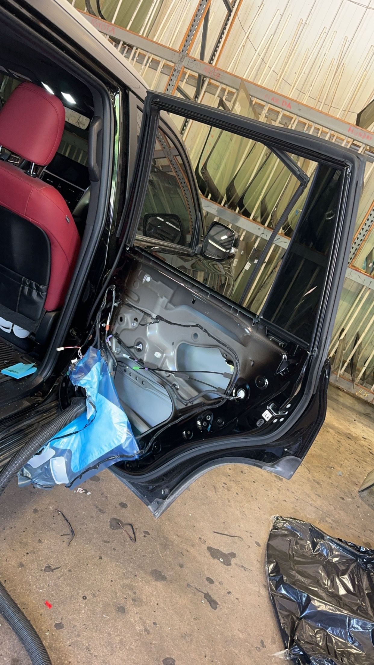Open car door with damaged interior and shattered glass on the ground