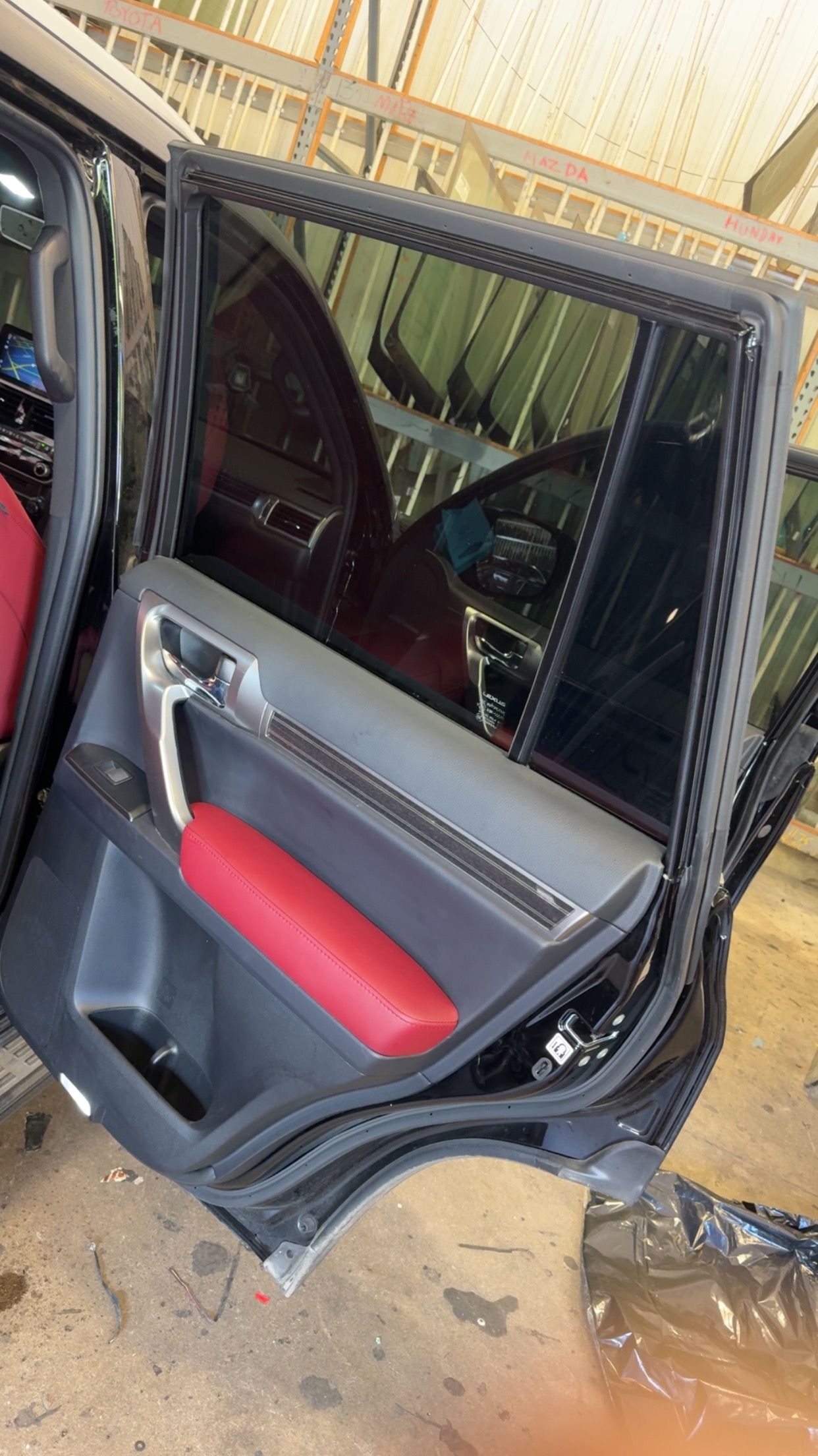 Open car door with red and gray interior panel and damaged trim.