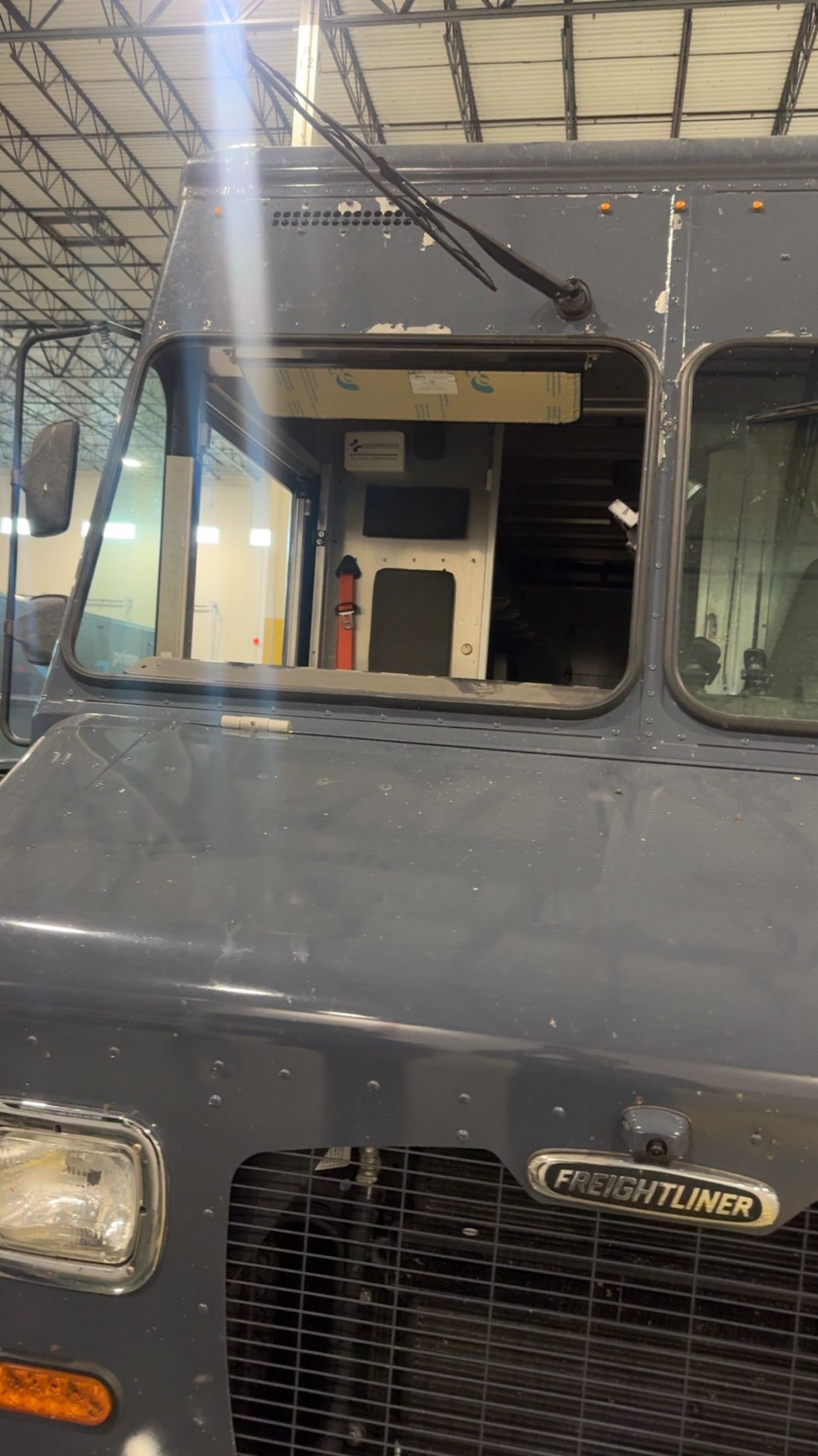 Front of a gray vintage truck parked indoors, showing windshield and grille.
