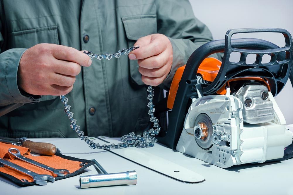 A Man is Fixing a Chainsaw on a Table — Coffs Chainsaw and Mower in Bellingen, NSW
