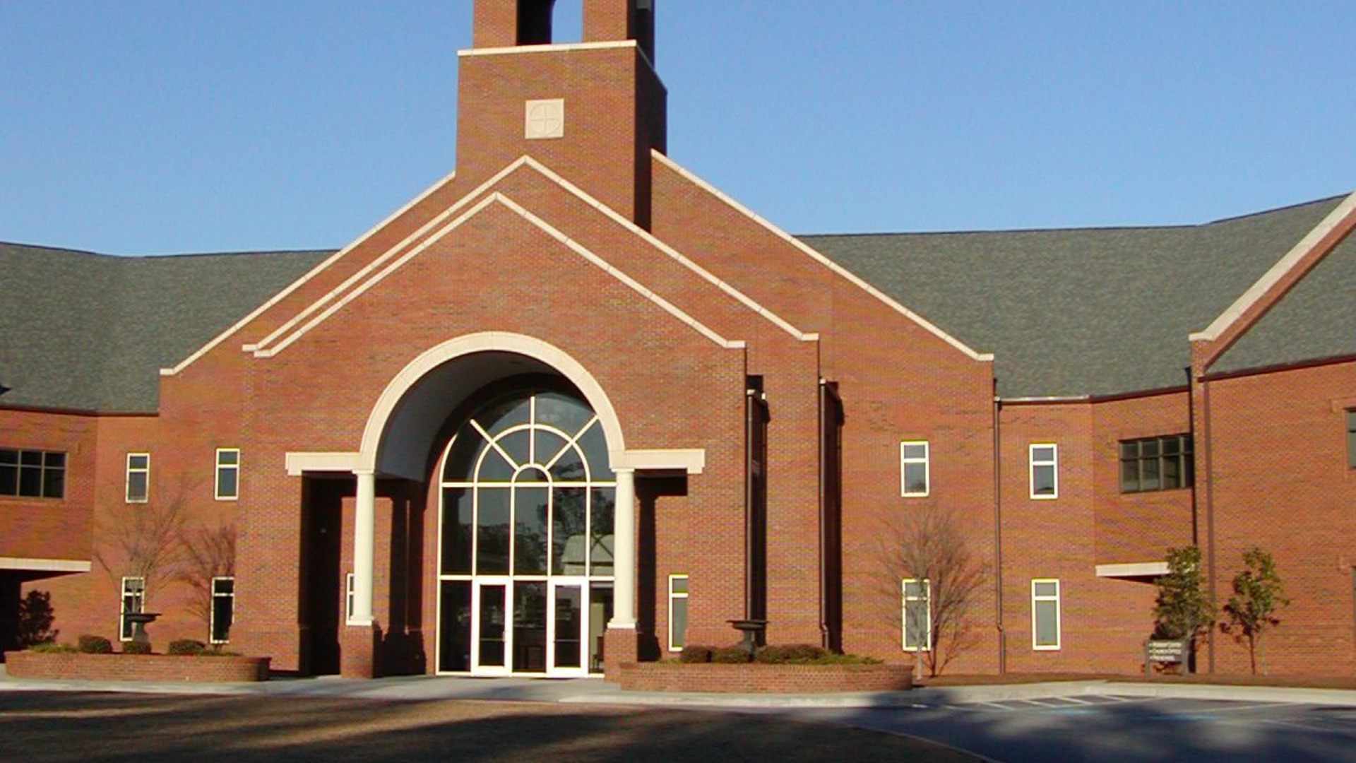 Brick church building with arched entrance and a bell tower.
