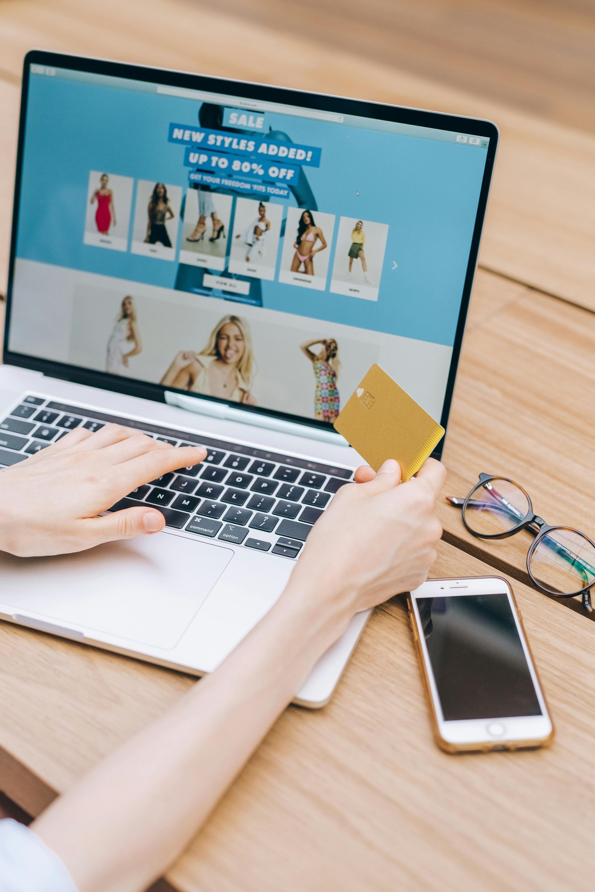 A person is holding a credit card while using a laptop computer.