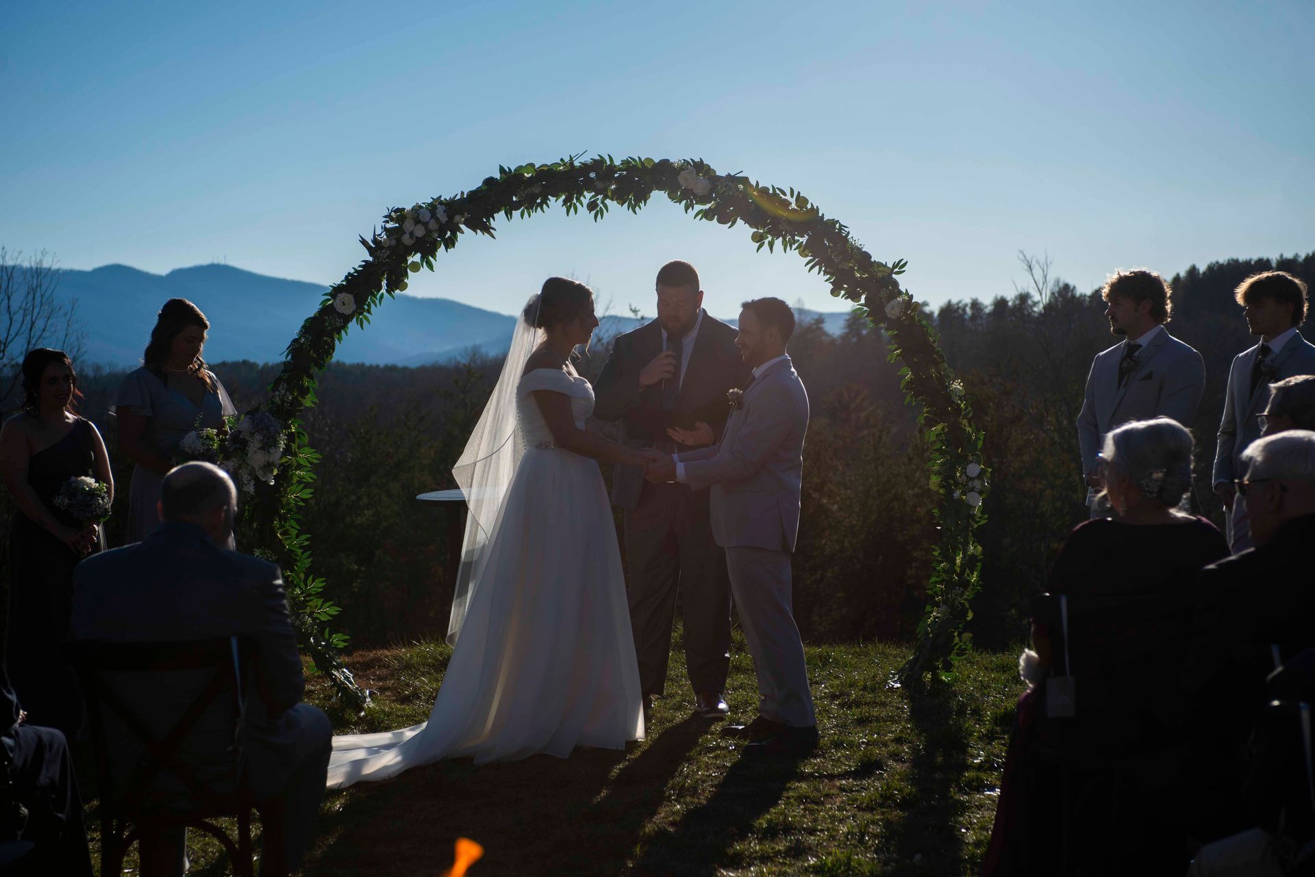 Couple standing beneath circular ceremony arch with mountain views during outdoor wedding in Blue Ridge