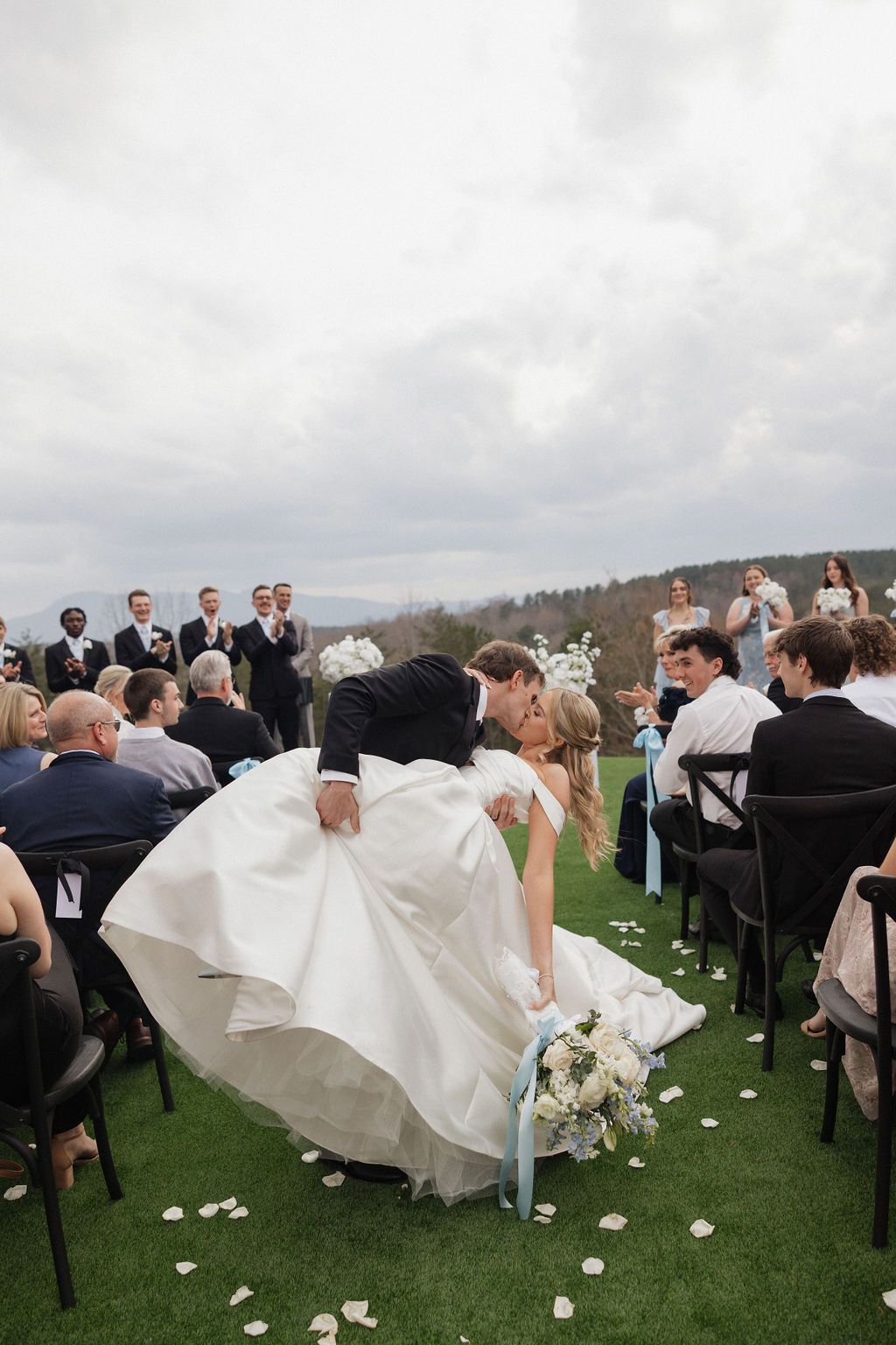 Bride and groom walking down aisle after outdoor ceremony with guests celebrating around them