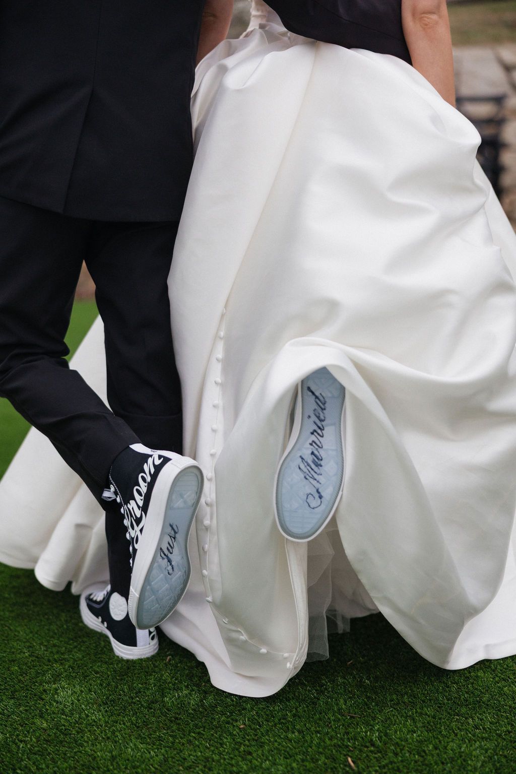 Bride lifting wedding dress to reveal sneakers during playful outdoor wedding portrait