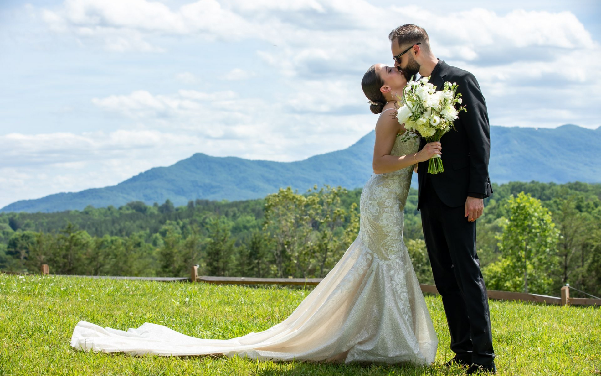 Embracing couple with NC Mountains behind them, just married at Serenity Ridge