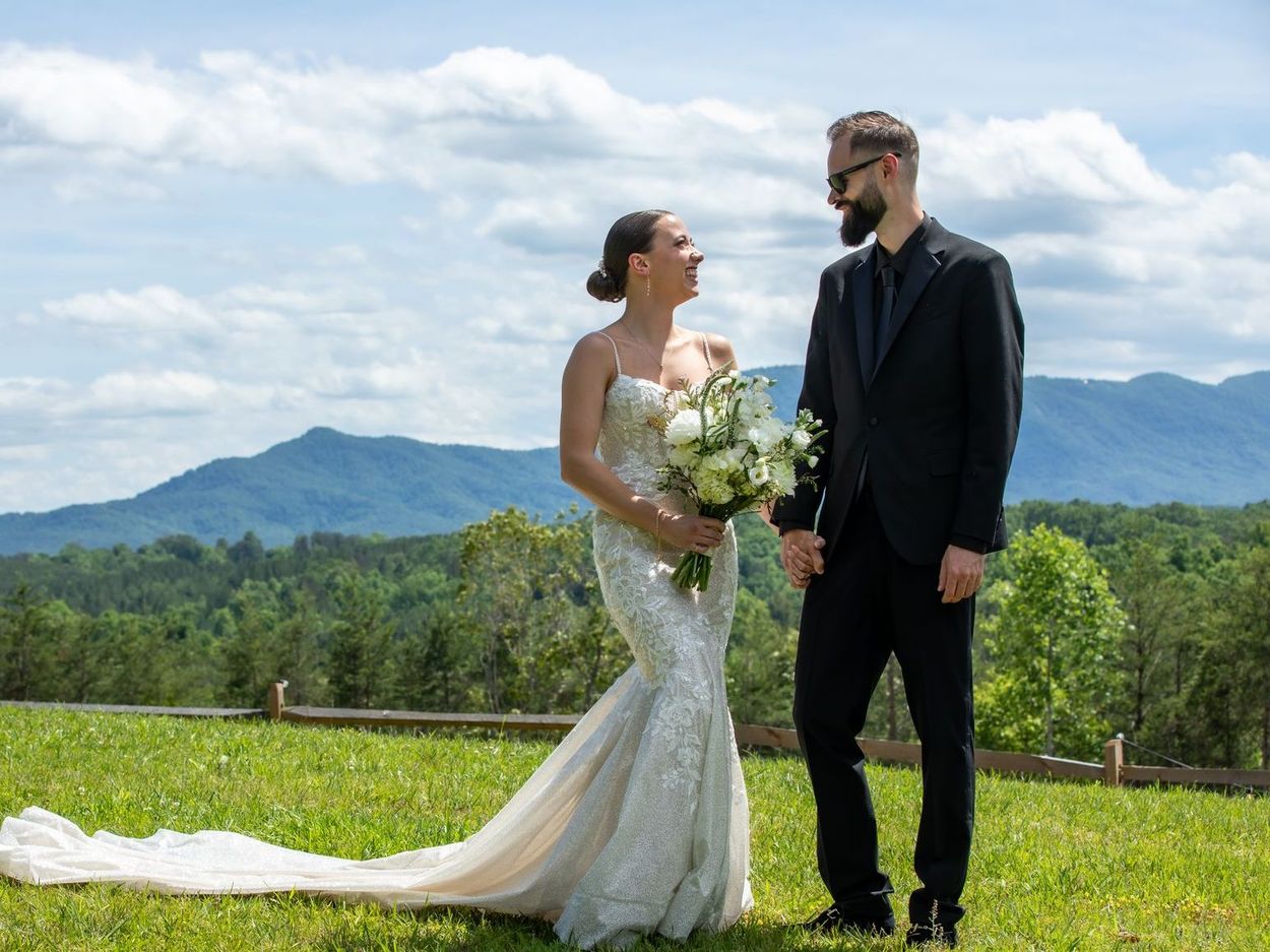 Bride with flowing gown and groom gazing lovingly in mountaintop ceremony at Serenity Ridge
