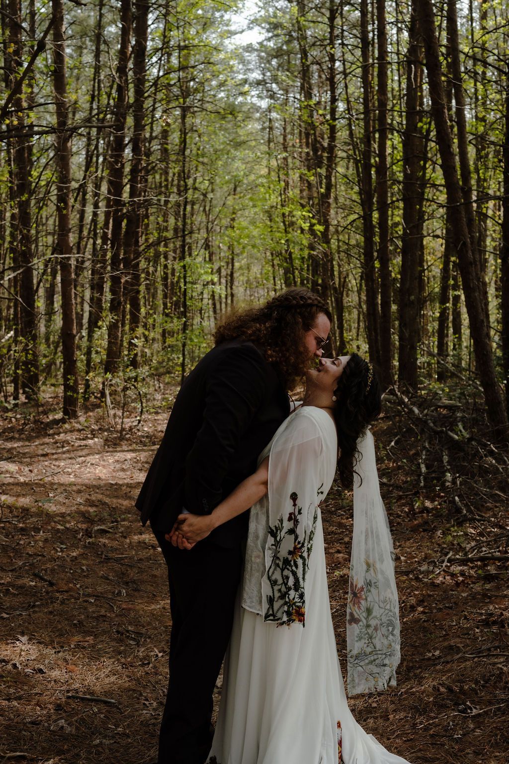 Bride and groom embracing in wooded setting during romantic mountain wedding portrait session