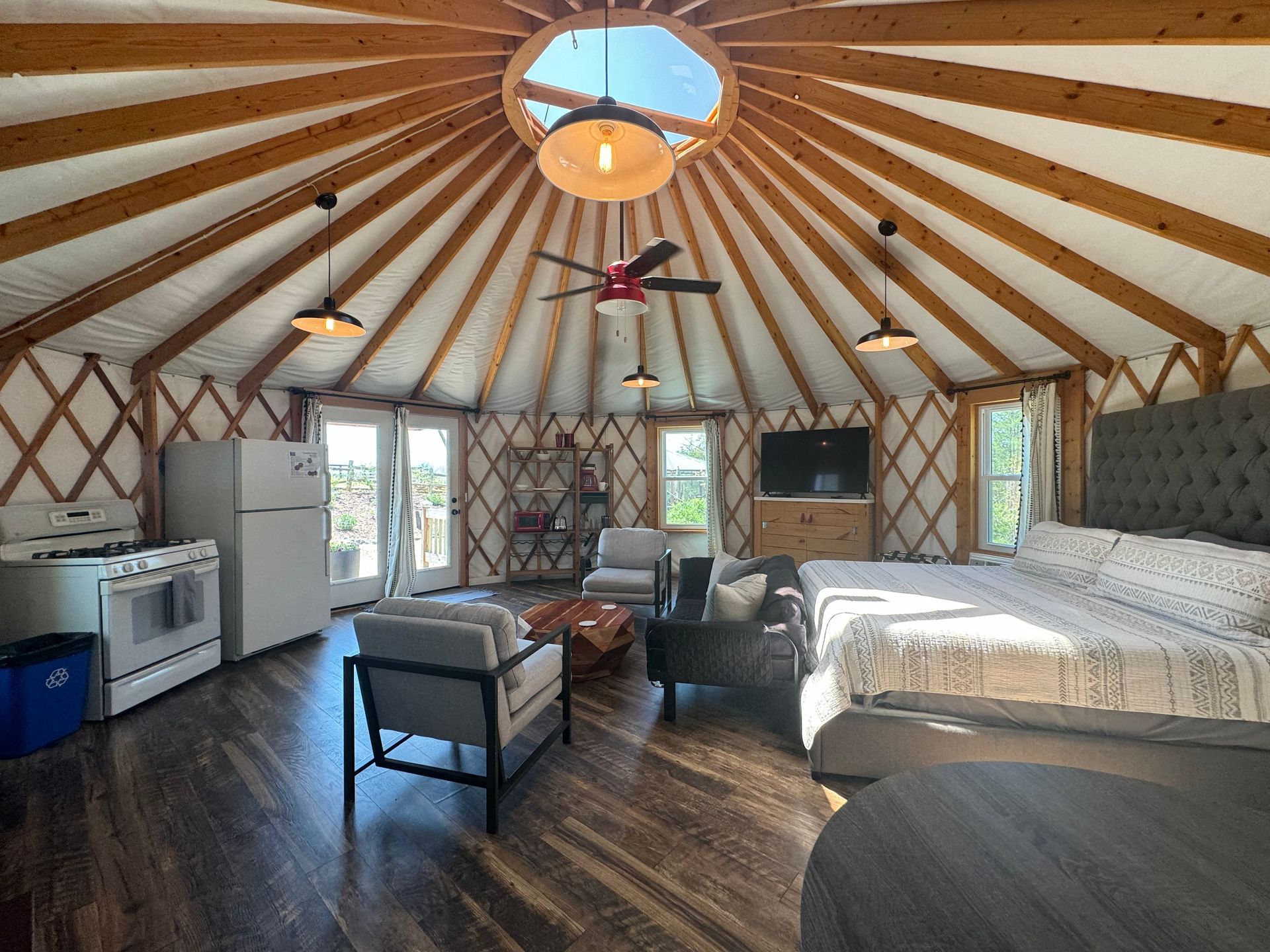 Living area inside glamping yurt with seating and TV at Serenity Ridge