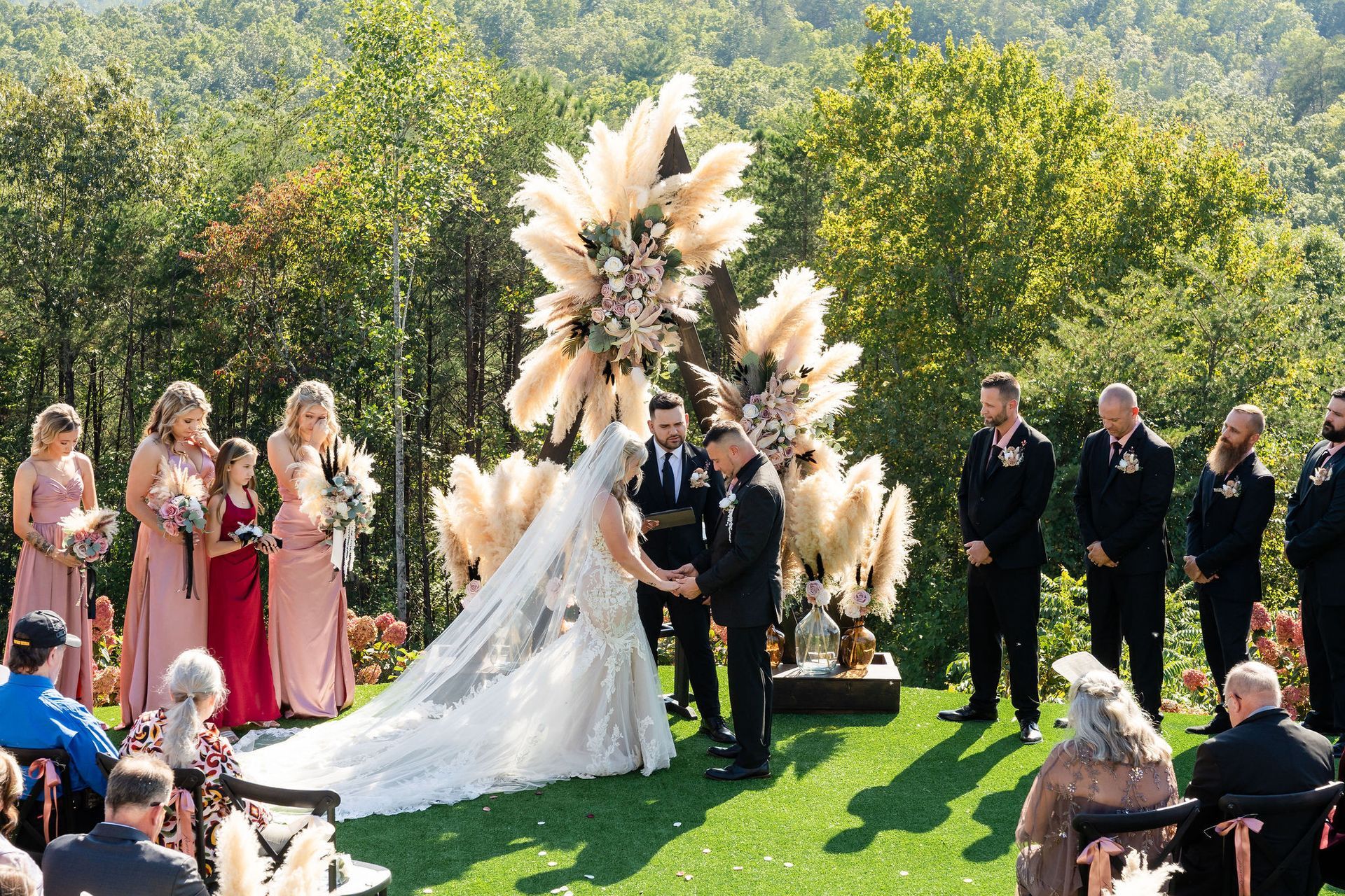 Bride and groom exchanging vows beneath statement floral arch during garden-style mountain wedding