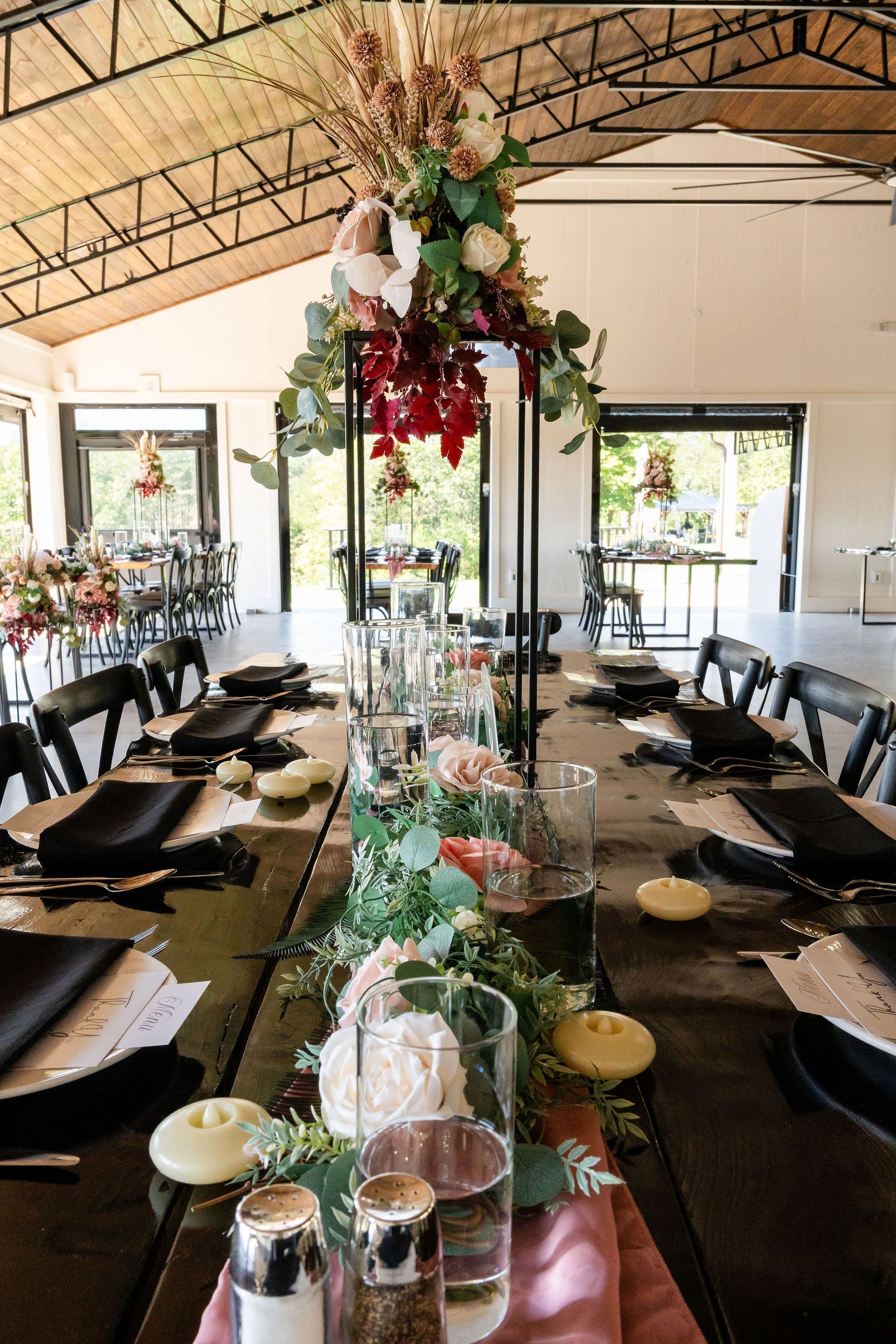 Elegant wedding reception table setup with greenery and long dining tables inside open-air pavilion