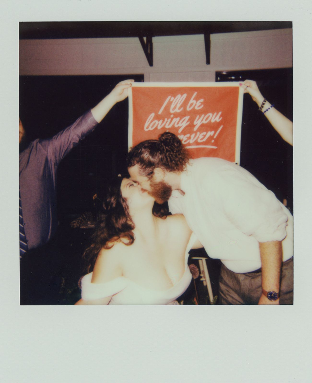 Bride and groom dancing during lively wedding reception celebration beneath custom party signage