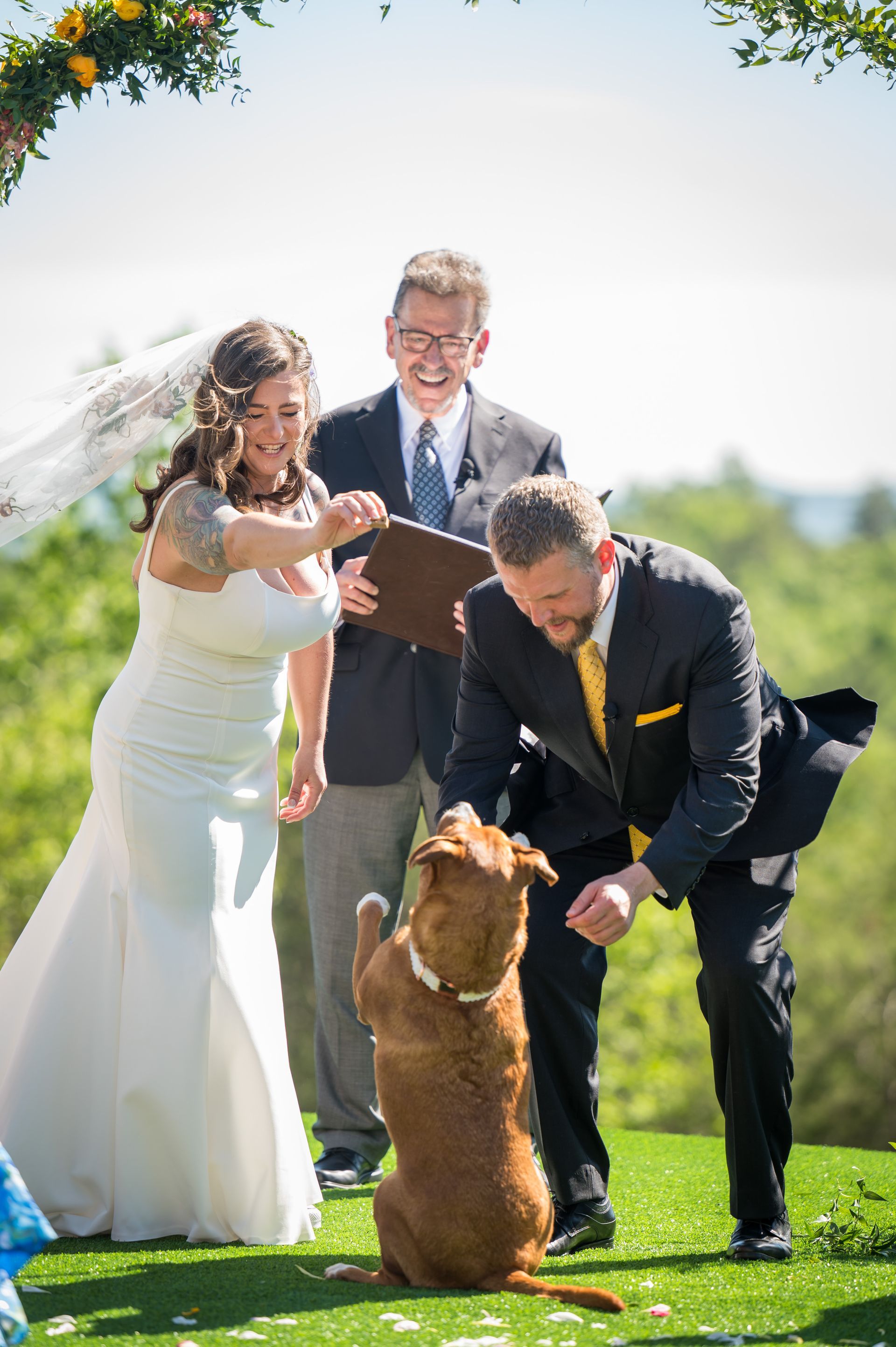 Bride and groom celebrating with their dog during outdoor mountain wedding ceremony