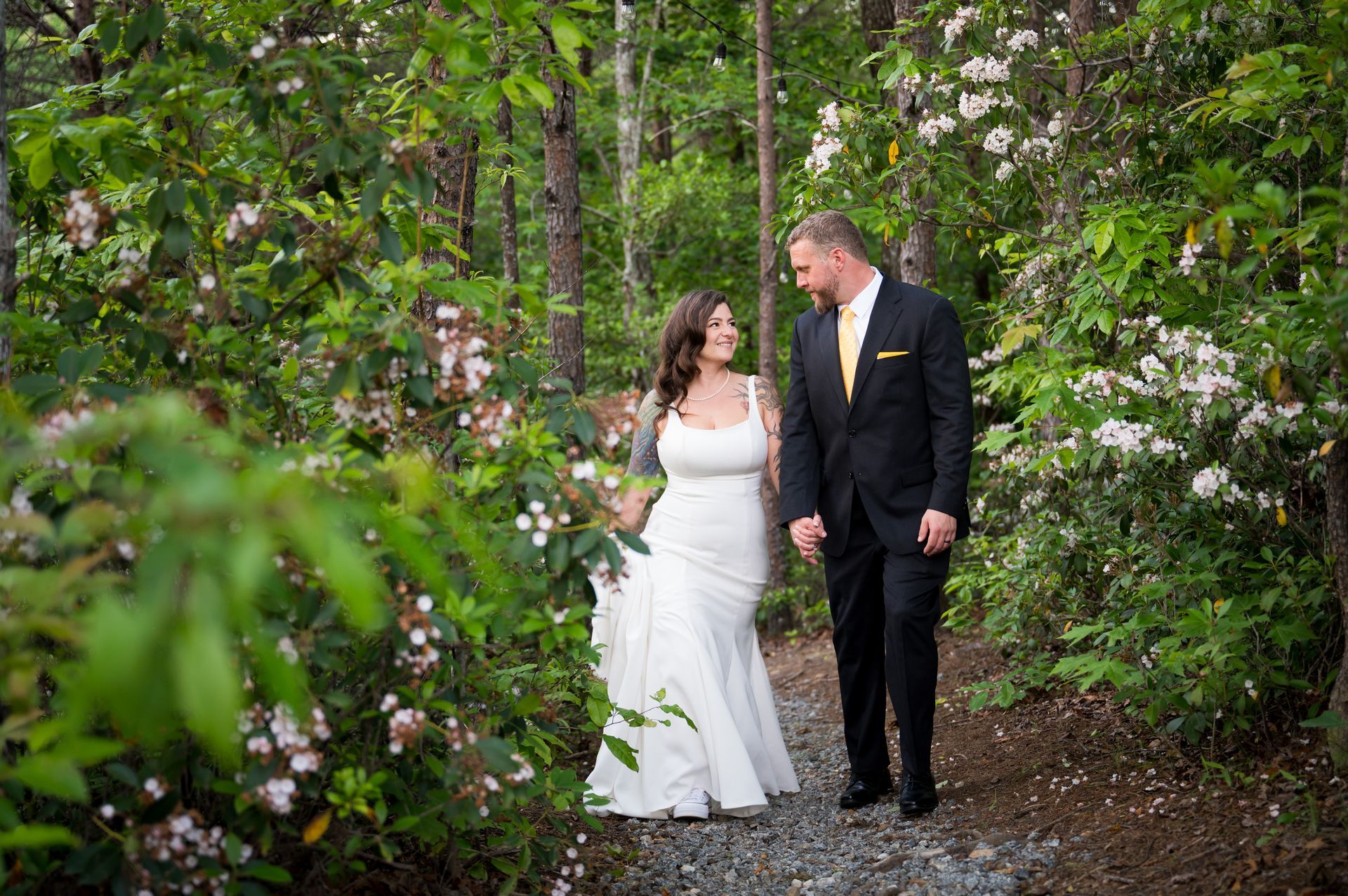 Bride and groom walking together through garden pathway at North Carolina mountain wedding venue