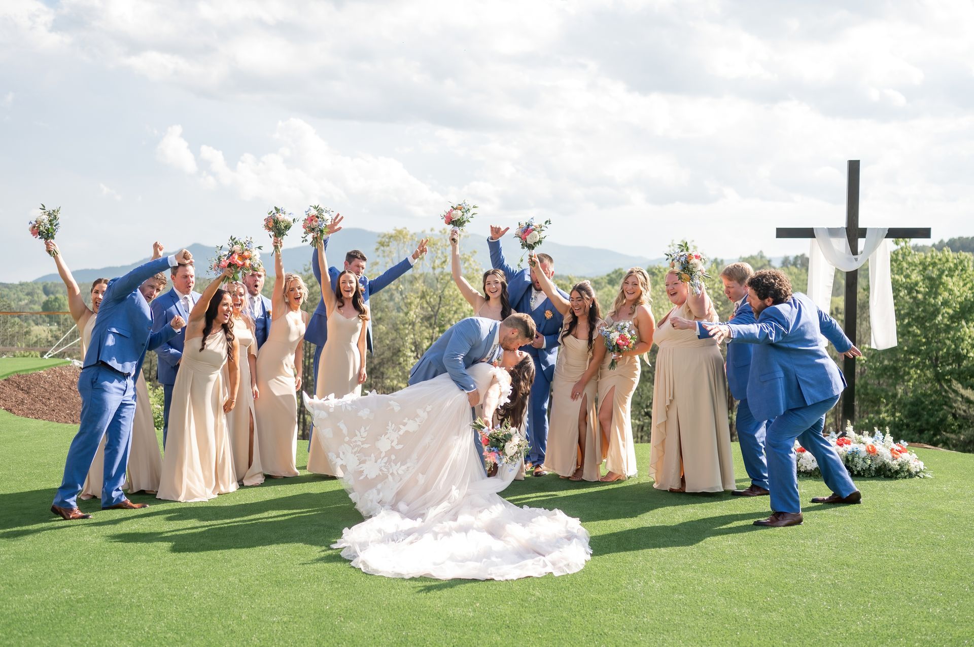 Newlyweds kissing after outdoor ceremony surrounded by guests at mountain wedding venue