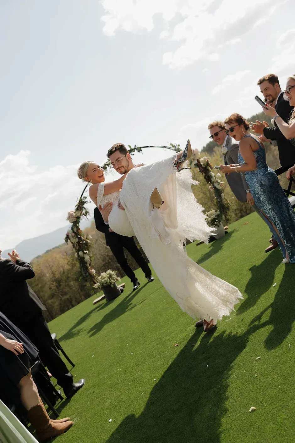 Groom carrying bride as they walk down the aisle after saying “I do” surrounded by mountains in WNC
