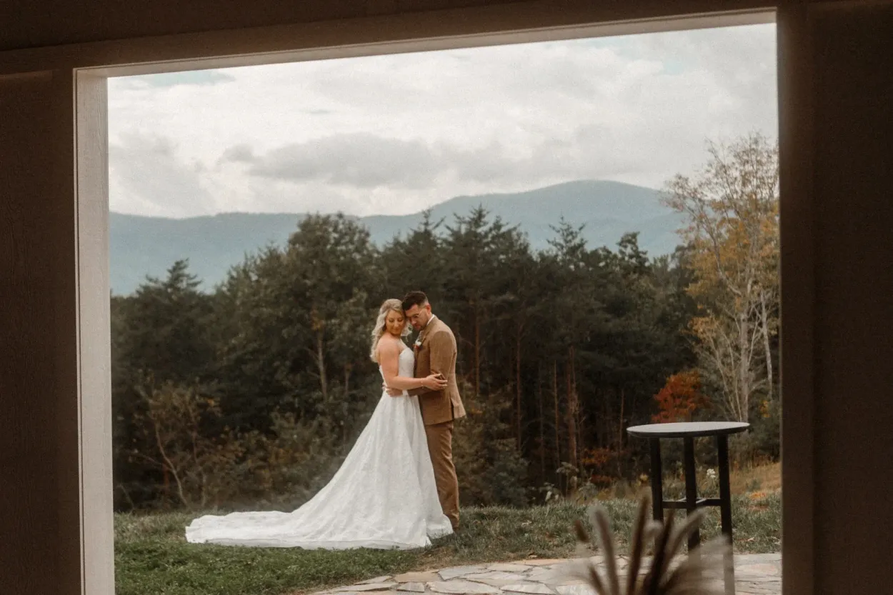 Couple embracing on ceremony lawn with panoramic Blue Ridge Mountain views in WNC at Serenity Ridge