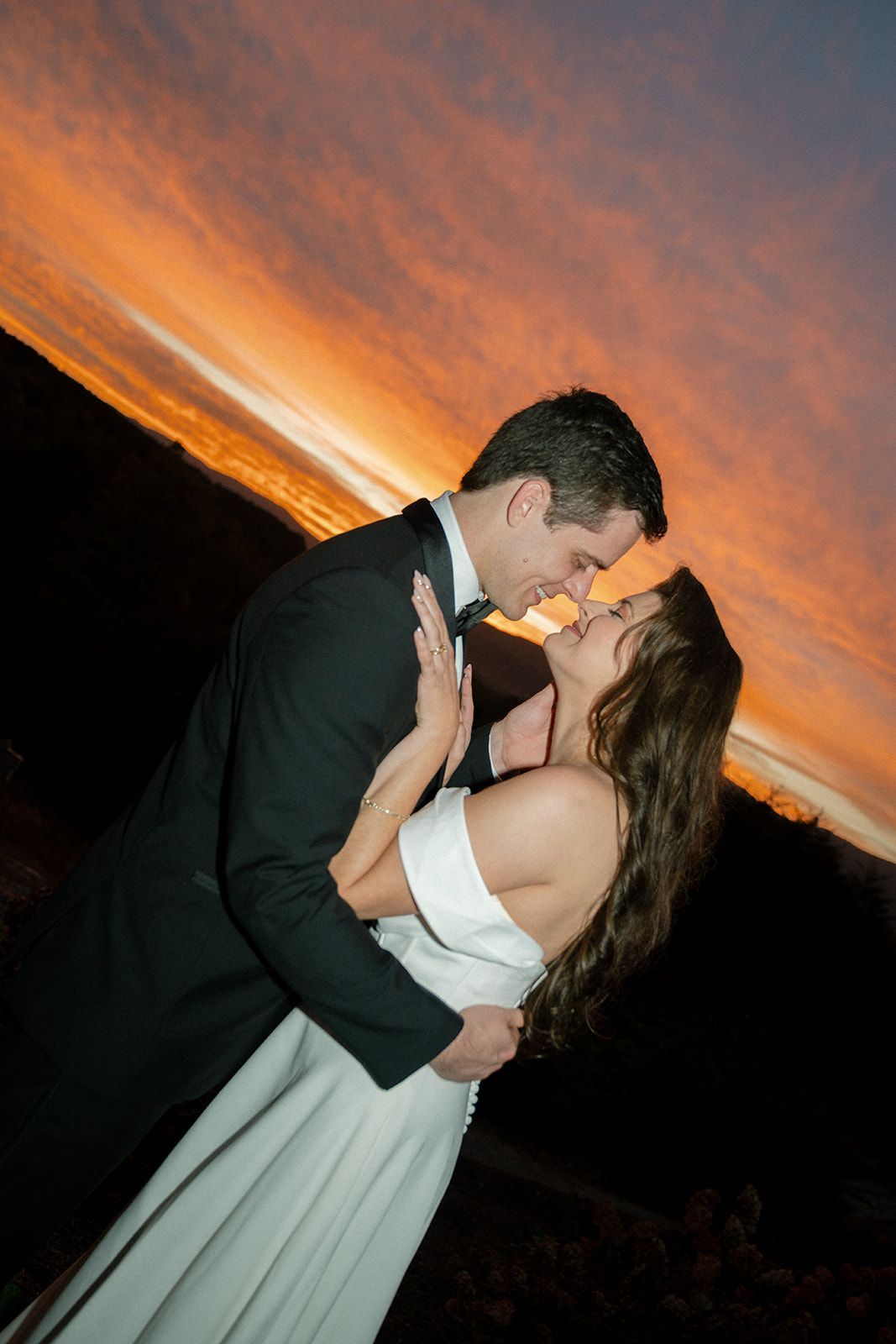 Bride and groom kissing at sunset with vibrant sky during mountain wedding in the Blue Ridge