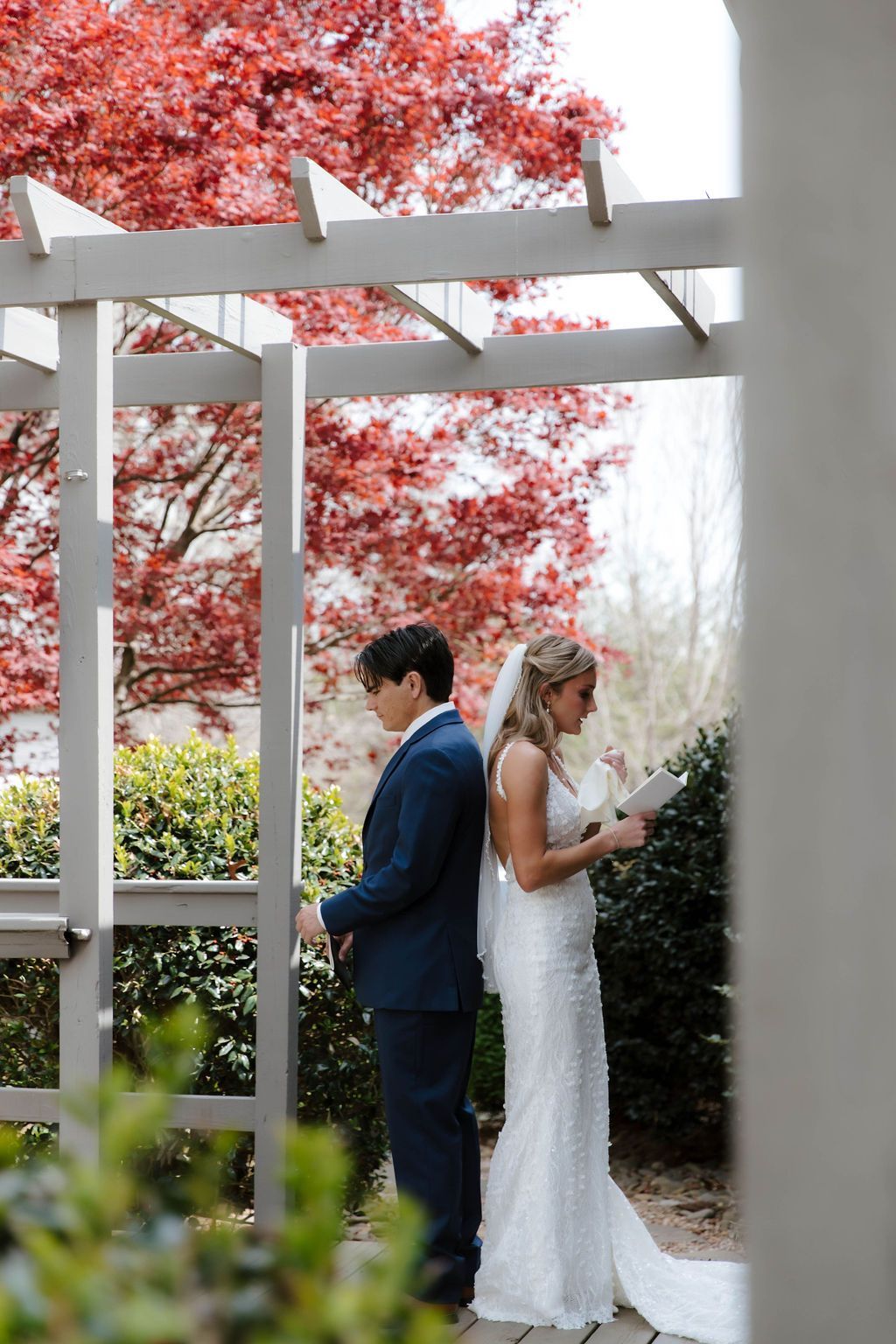 Bride and groom standing beneath pergola surrounded by autumn color at mountain wedding venue