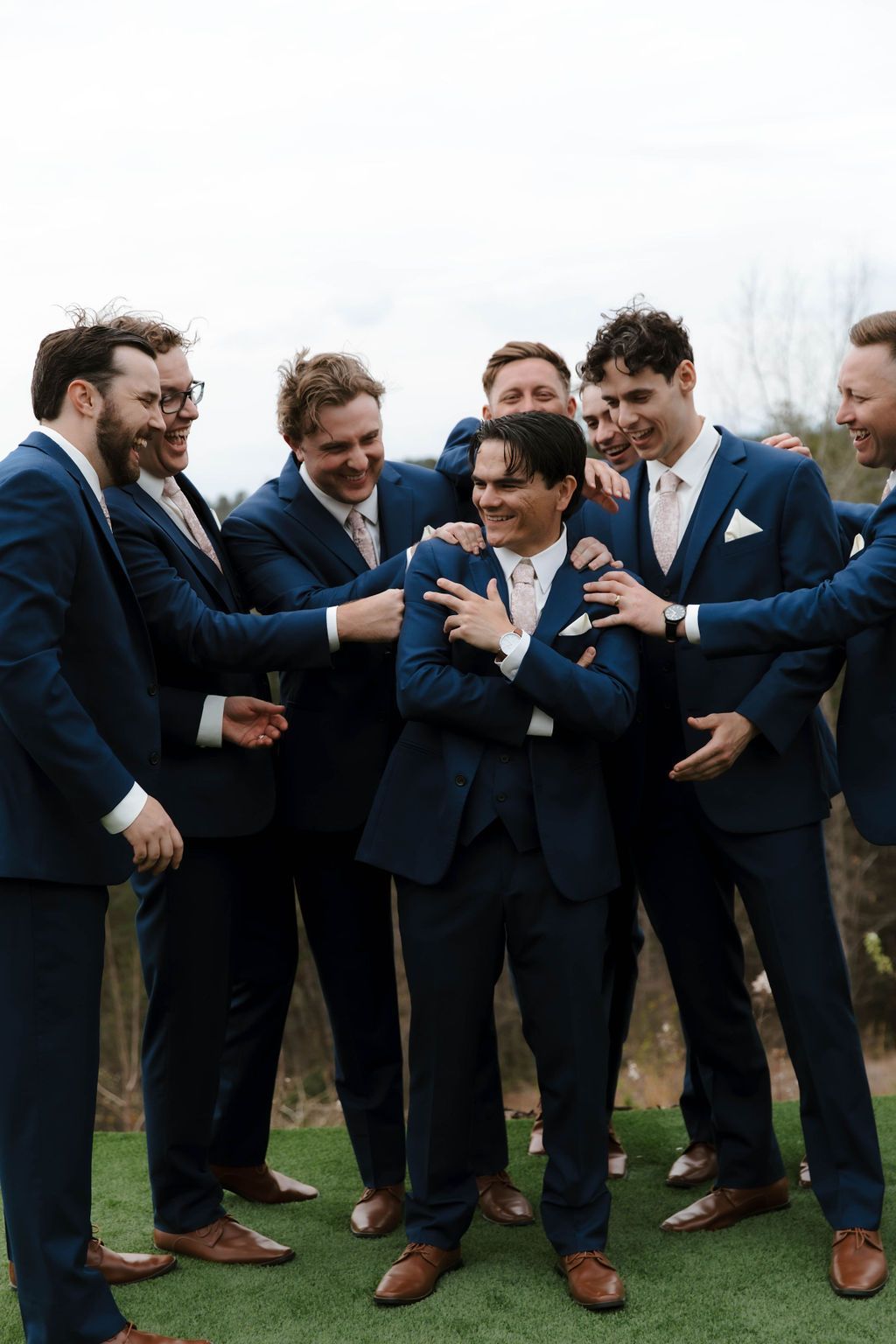Groomsmen sharing drinks and conversation before outdoor wedding ceremony in western North Carolina