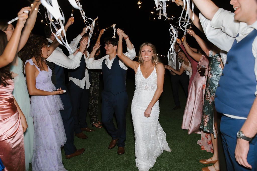 Bride dancing beneath streamers during energetic outdoor wedding reception celebration