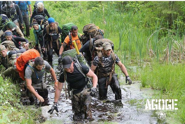 A group of people are walking through a muddy field