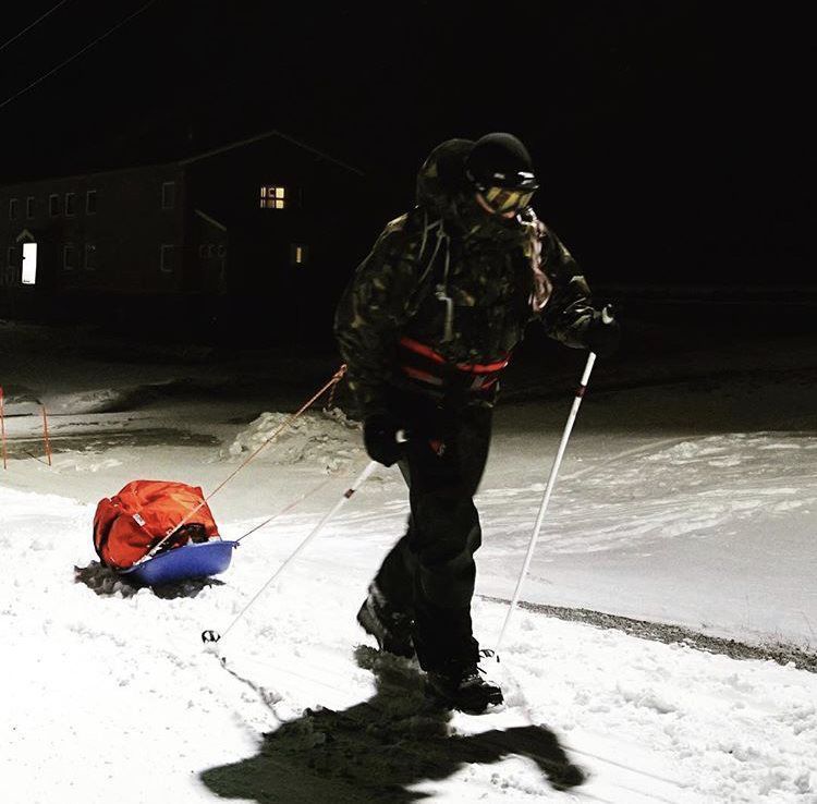 A person is pulling a sled in the snow at night
