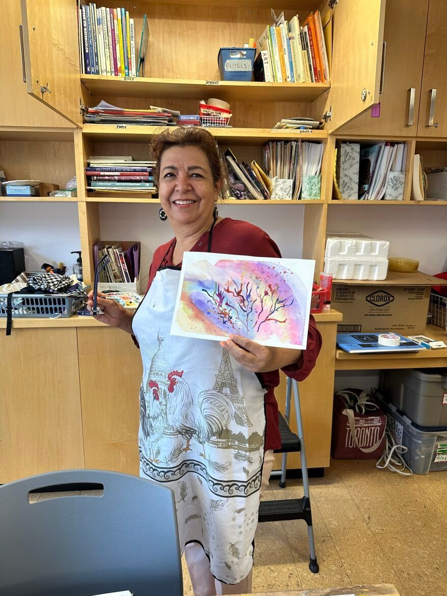 A woman is holding a painting in her hands in a room.
