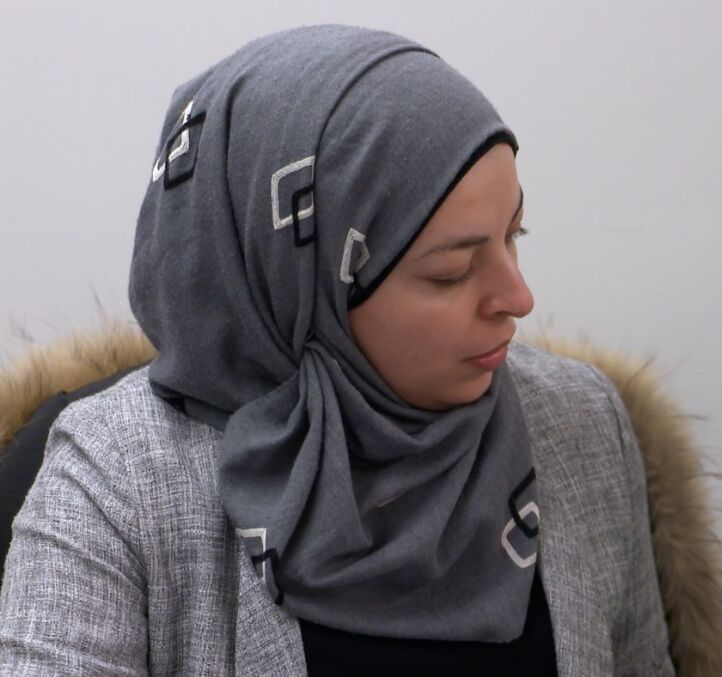 A woman wearing a gray scarf with the letter g on it