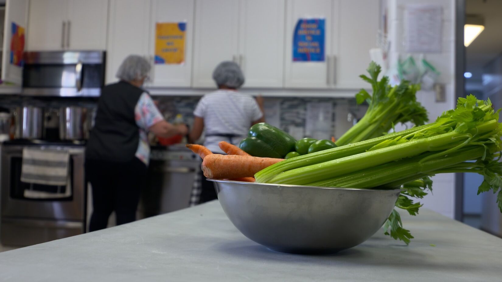 A bowl of vegetables is on a counter in a kitchen.