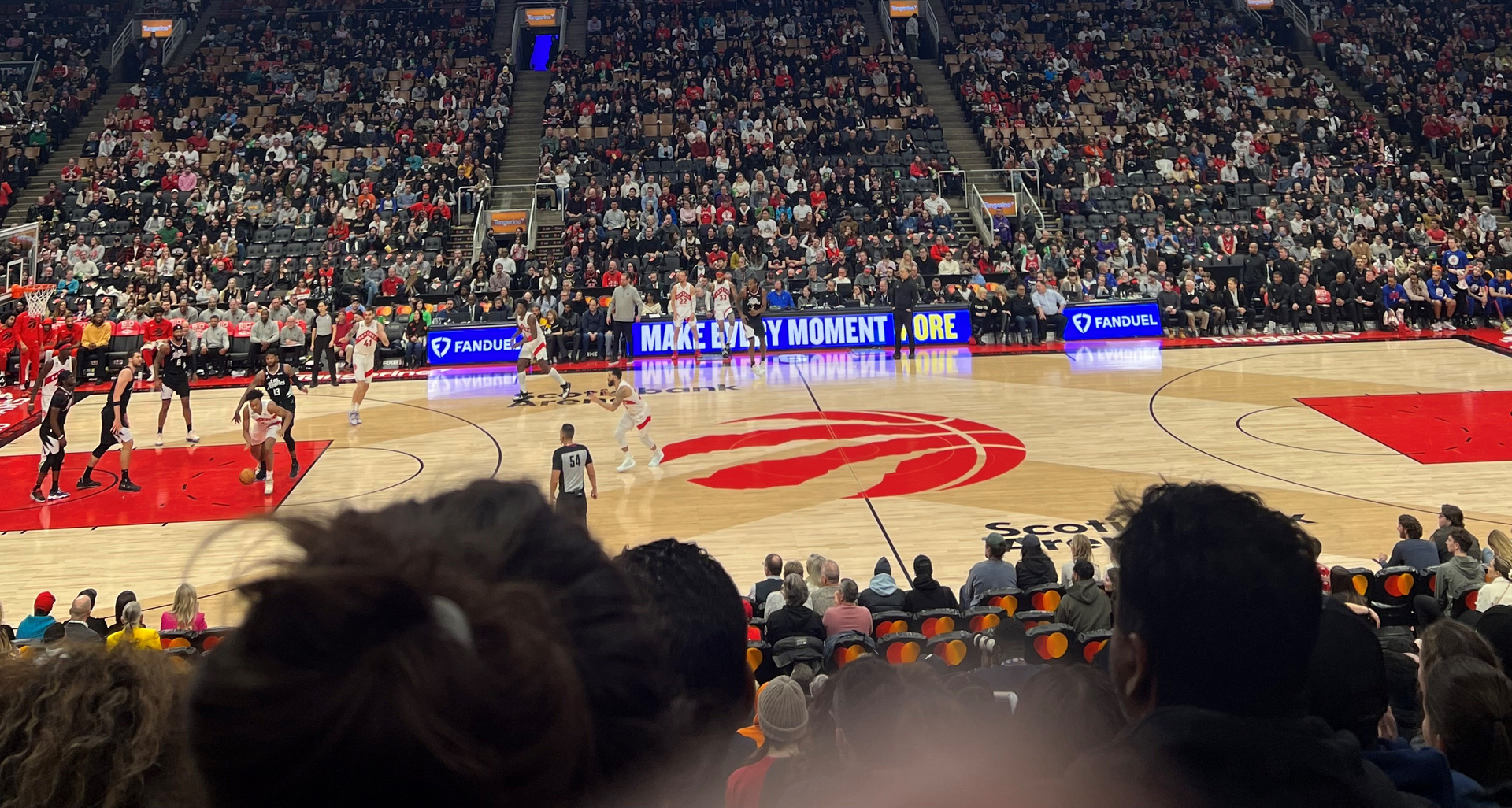 A crowd of people are watching a basketball game in a stadium.