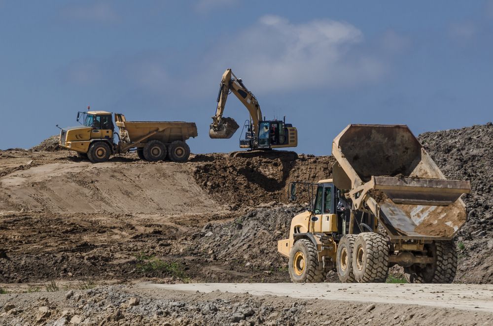 Construction Site With Excavator Loading a Dump Truck — Heller Excavation & Tree Services in Byron Bay, NSW