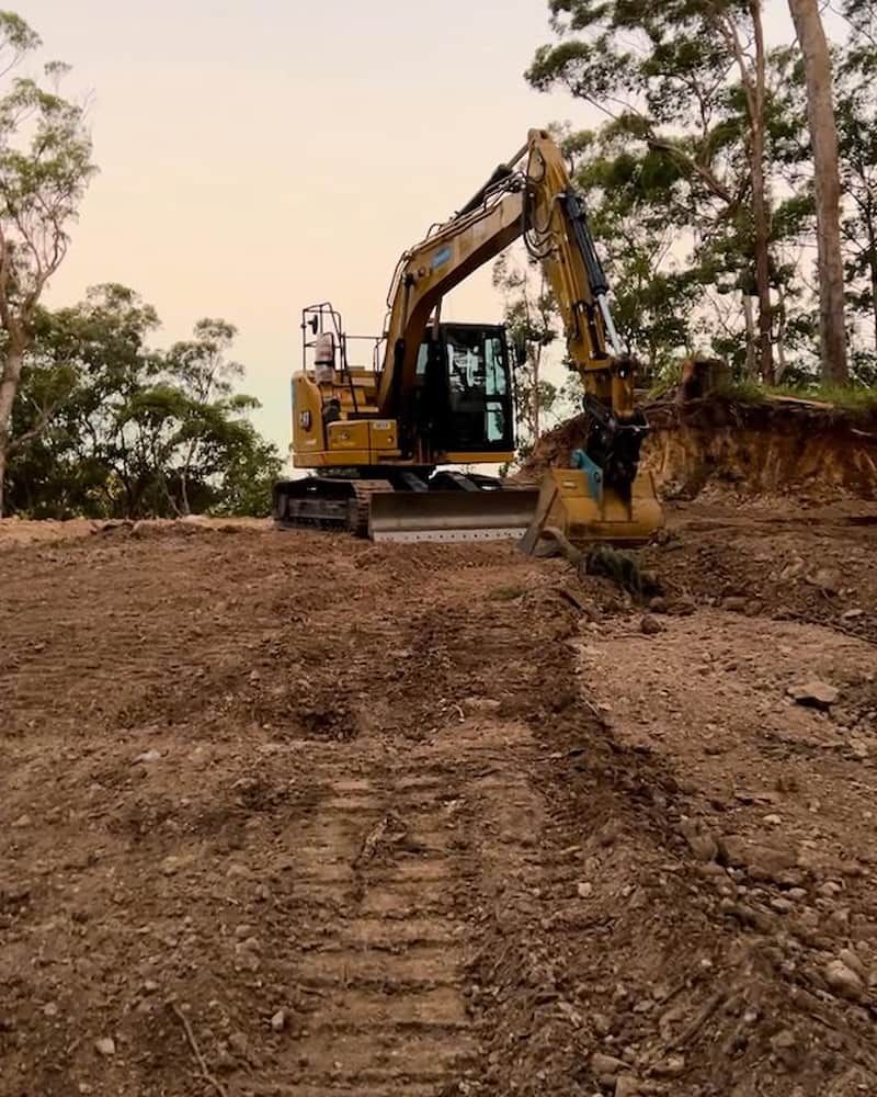 Yellow Excavator on a Dirt Hill, Trees — Heller Excavation & Tree Services in Mullumbimby, NSW