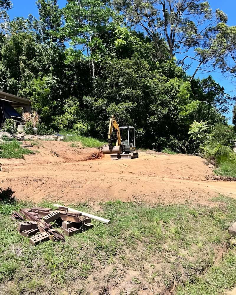Excavator on a Dirt Lot Clearing Land in Front of a House — Heller Excavation & Tree Services in Mullumbimby, NSW