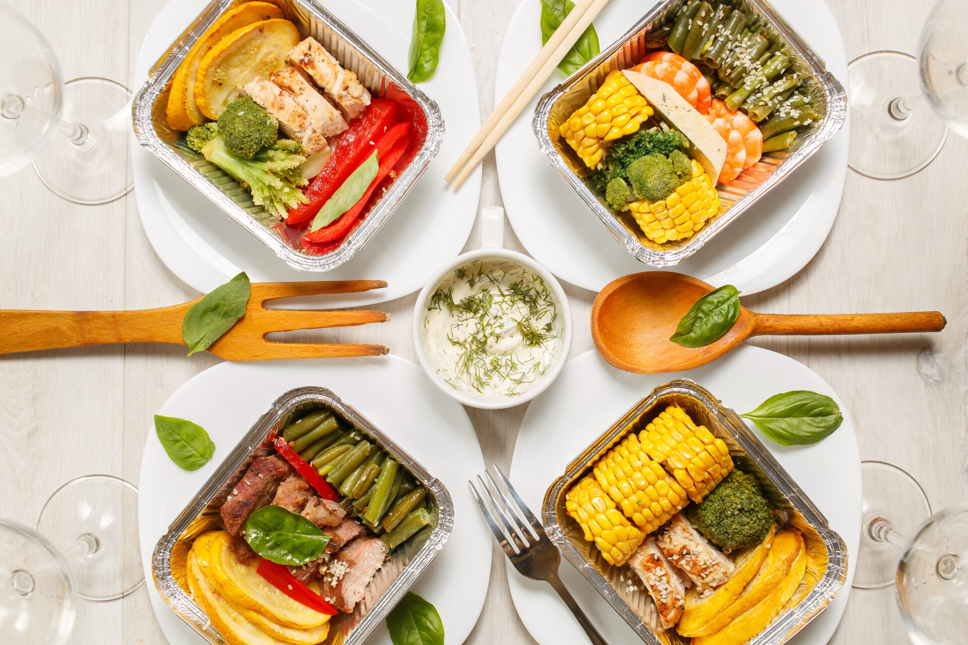 A table topped with four plates of food and utensils.
