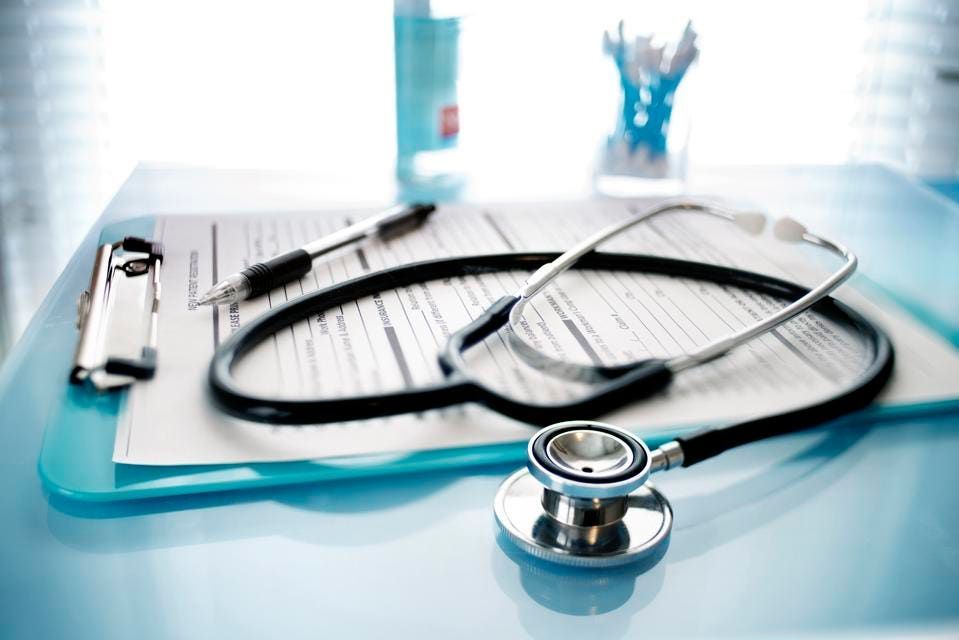 A stethoscope is sitting on top of a clipboard on a table.