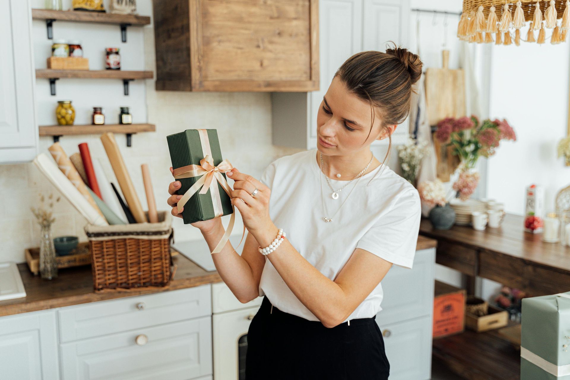 A woman is holding a gift box in her hands in a kitchen.