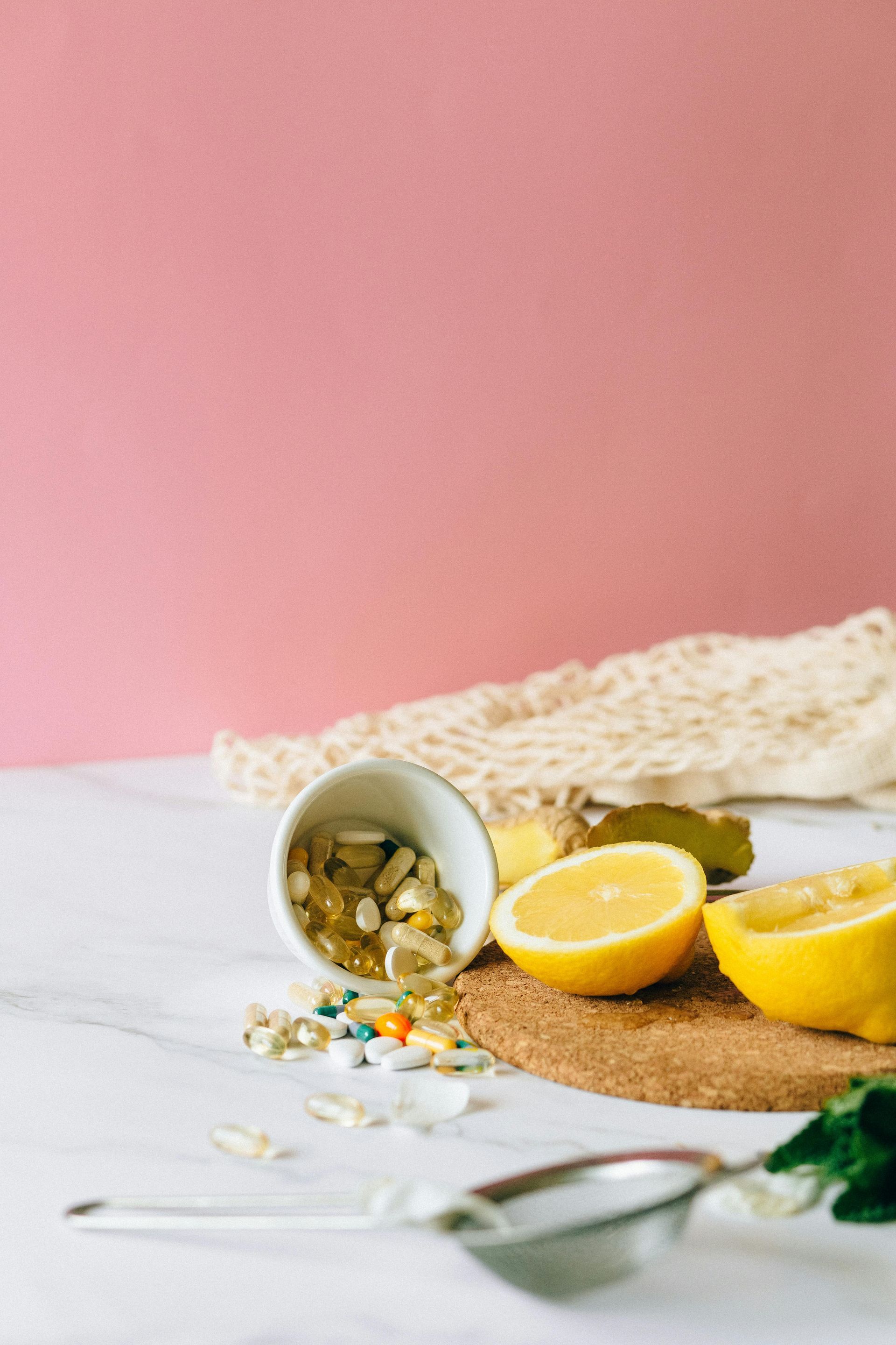 A bowl of vitamins , lemons , and a spoon on a table.