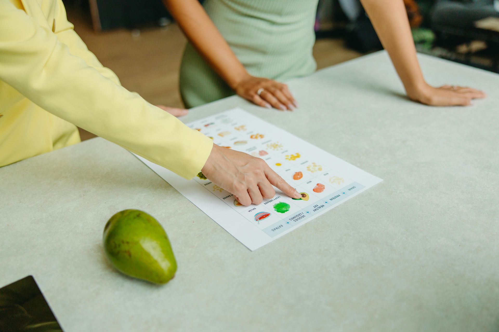 A woman is pointing at a piece of paper on a table.