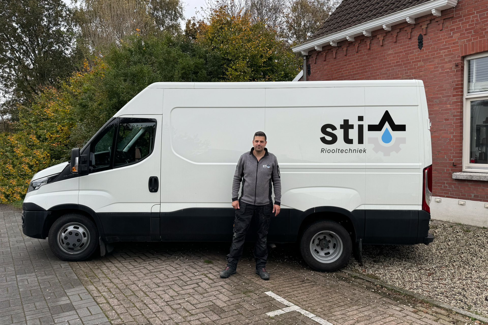 Een man staat naast een witte bestelbus met een 