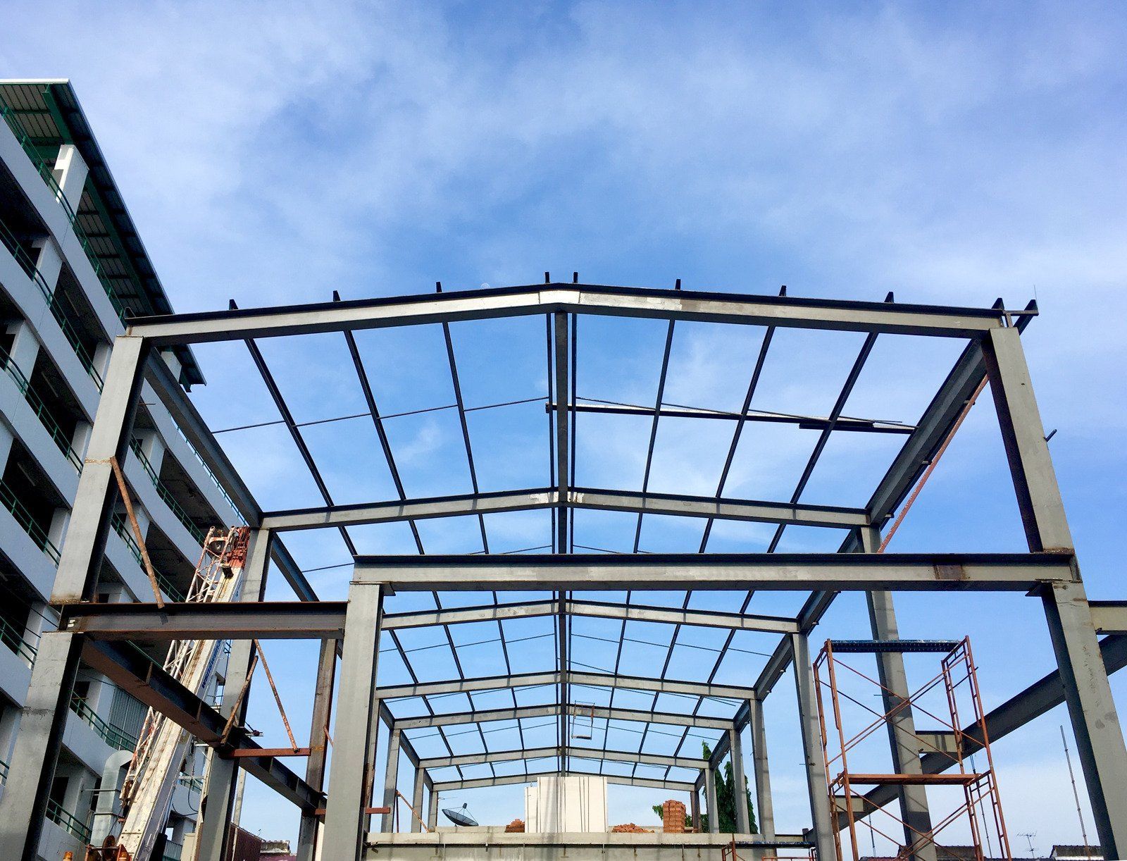 Steel framework of a building under construction, against a cloudy sky.