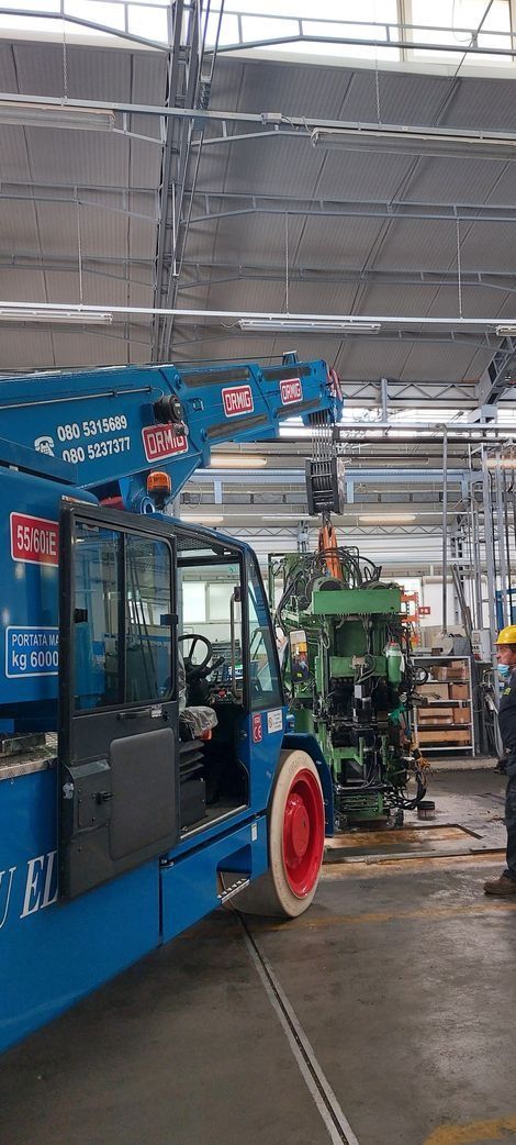 Trattori blu e verdi all'interno di un magazzino con pavimento bagnato e luci dall'alto
