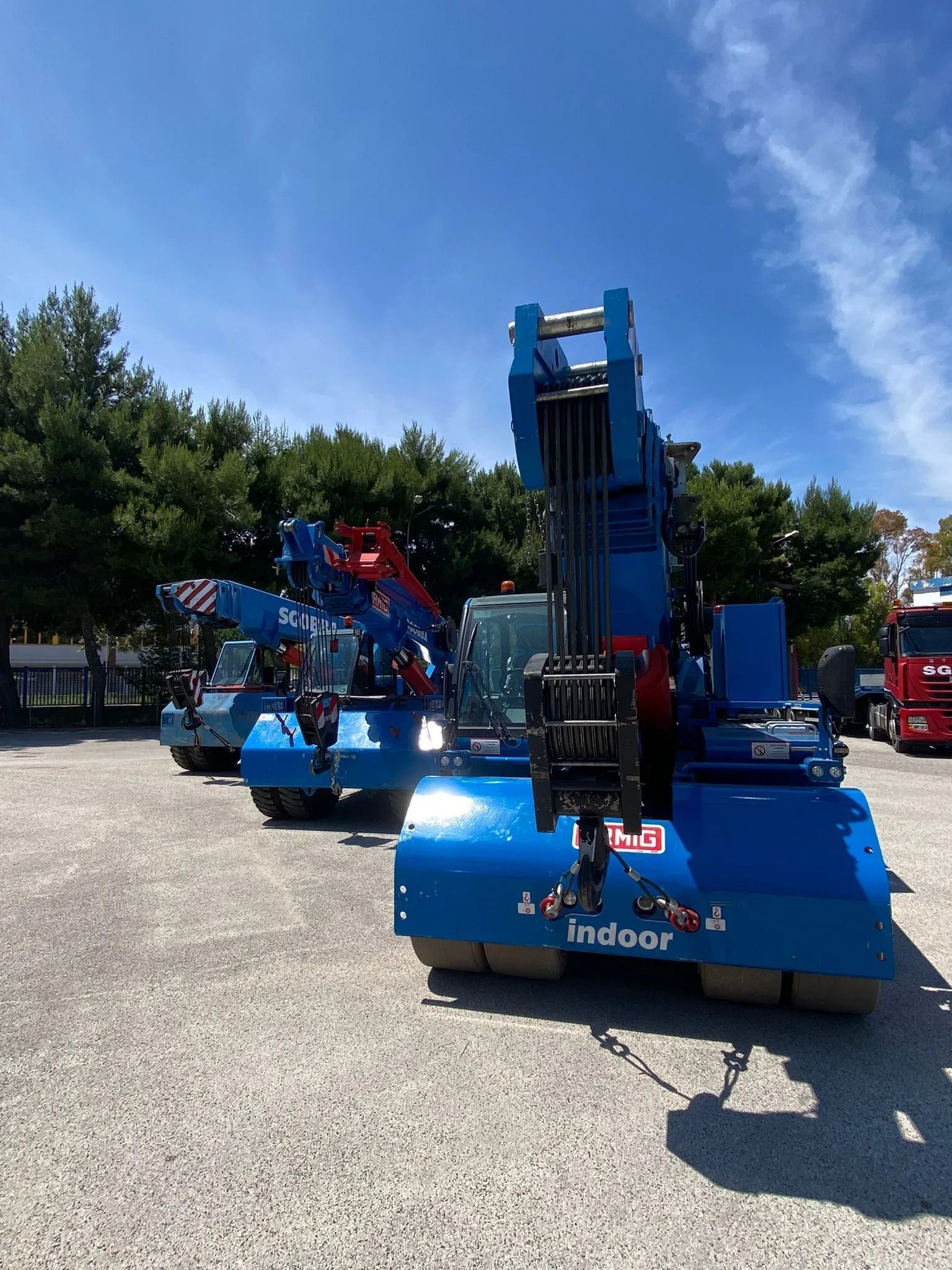 Macchinari industriali blu esposti all'aperto su un terreno ghiaioso sotto un cielo soleggiato.