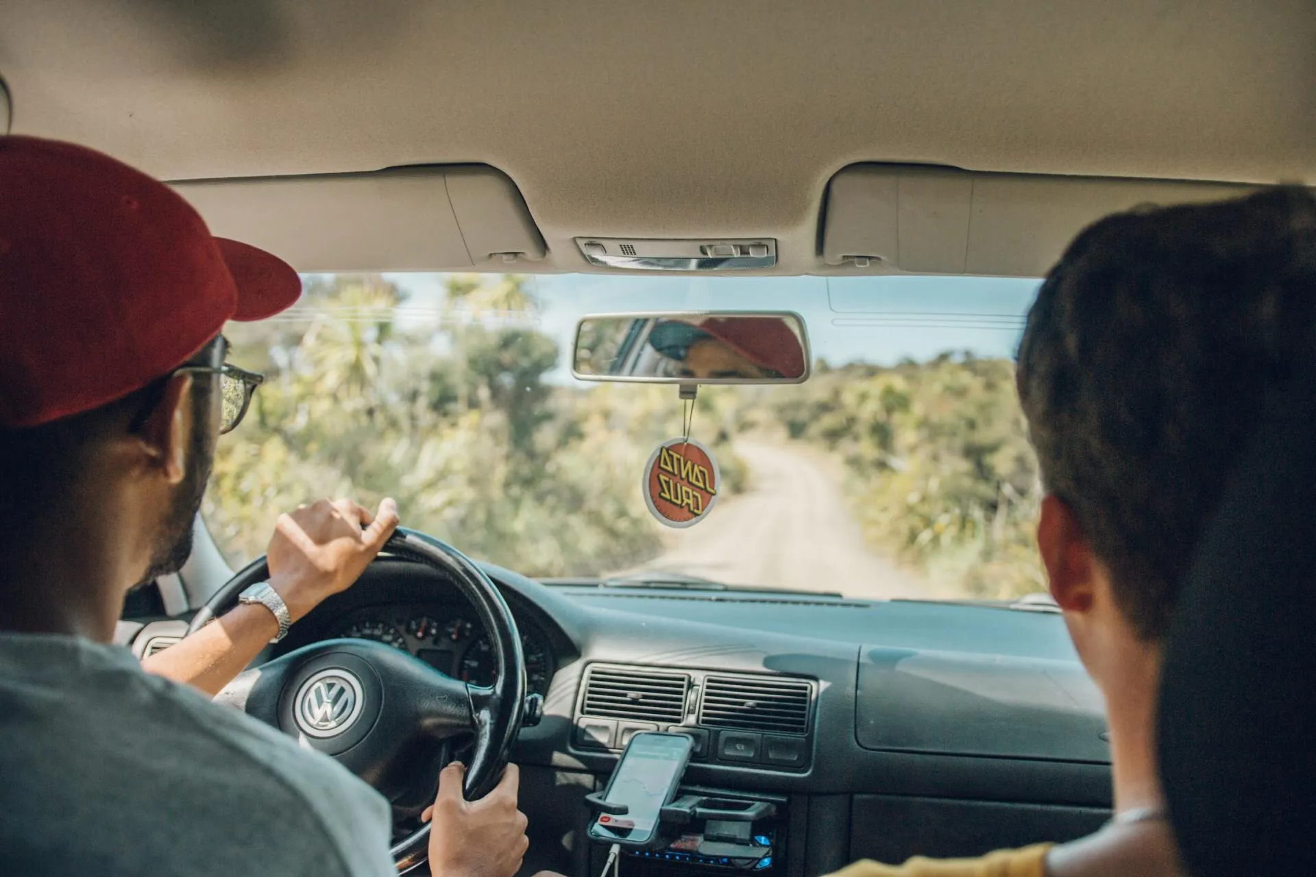 Two friends are driving an older Volkswagen Golf on a road trip with a recently replaced windshield.