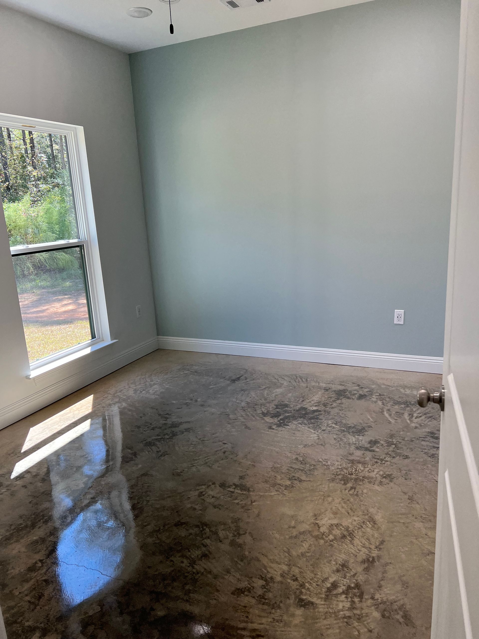 room with lots of natural light. light colored walls and stained concrete floor