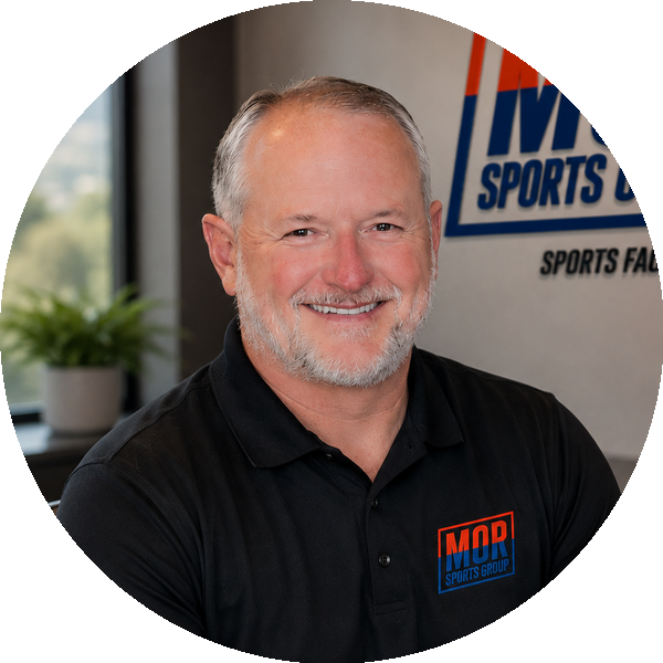 Smiling man in black polo with MOD Sports logo, seated in an office setting