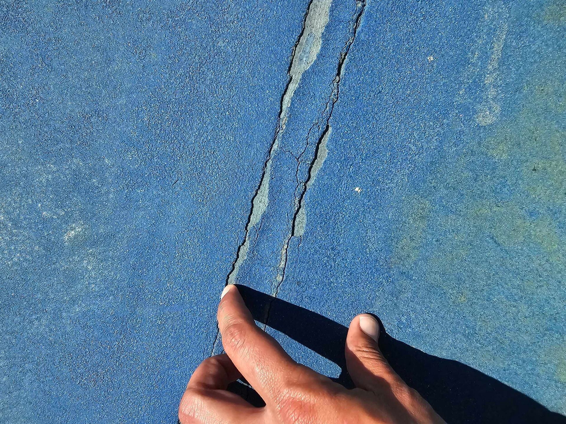 Hands tracing a crack in a blue textured surface
