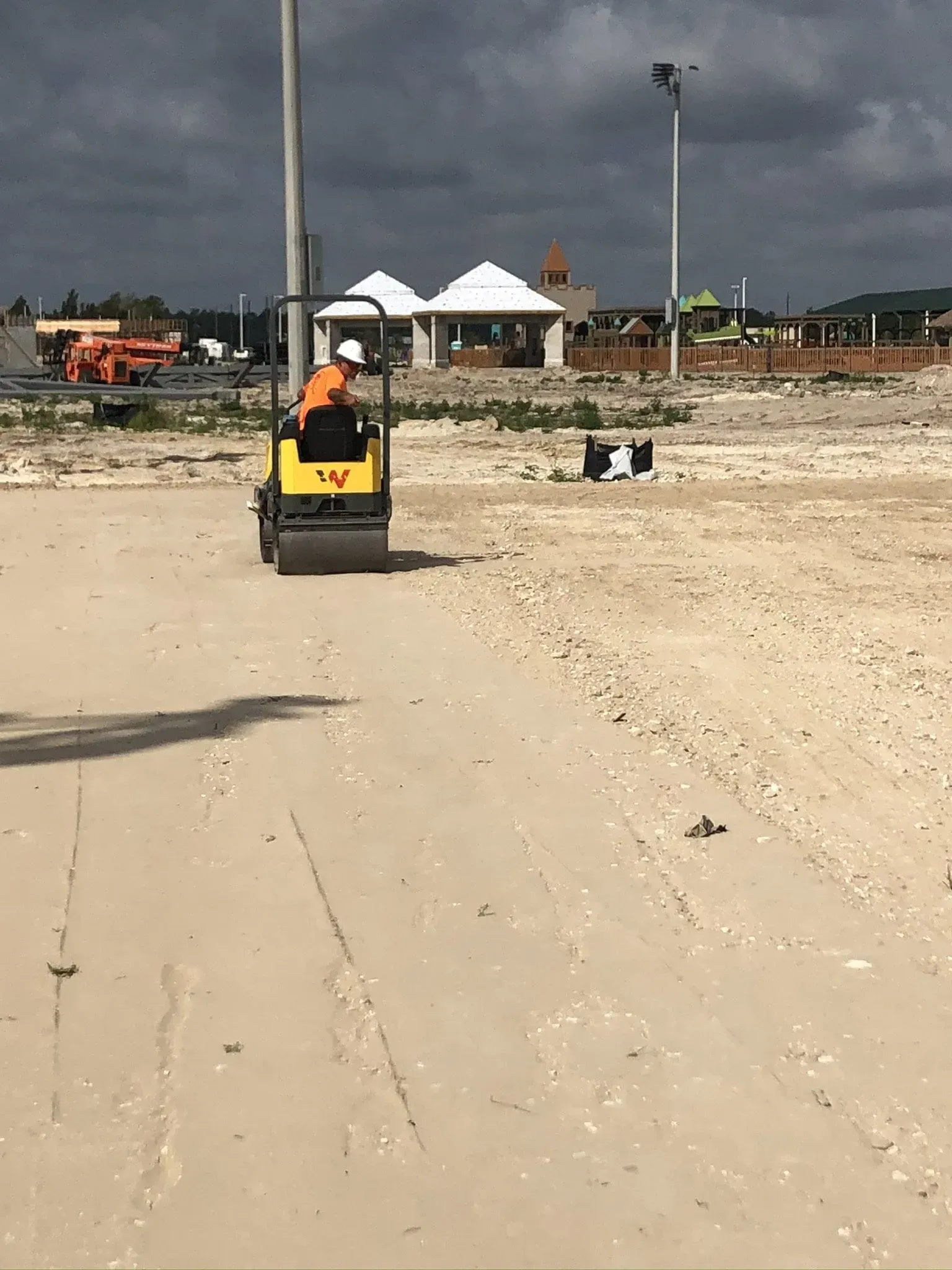 Yellow construction vehicle on a sandy site with tents and equipment in the background.