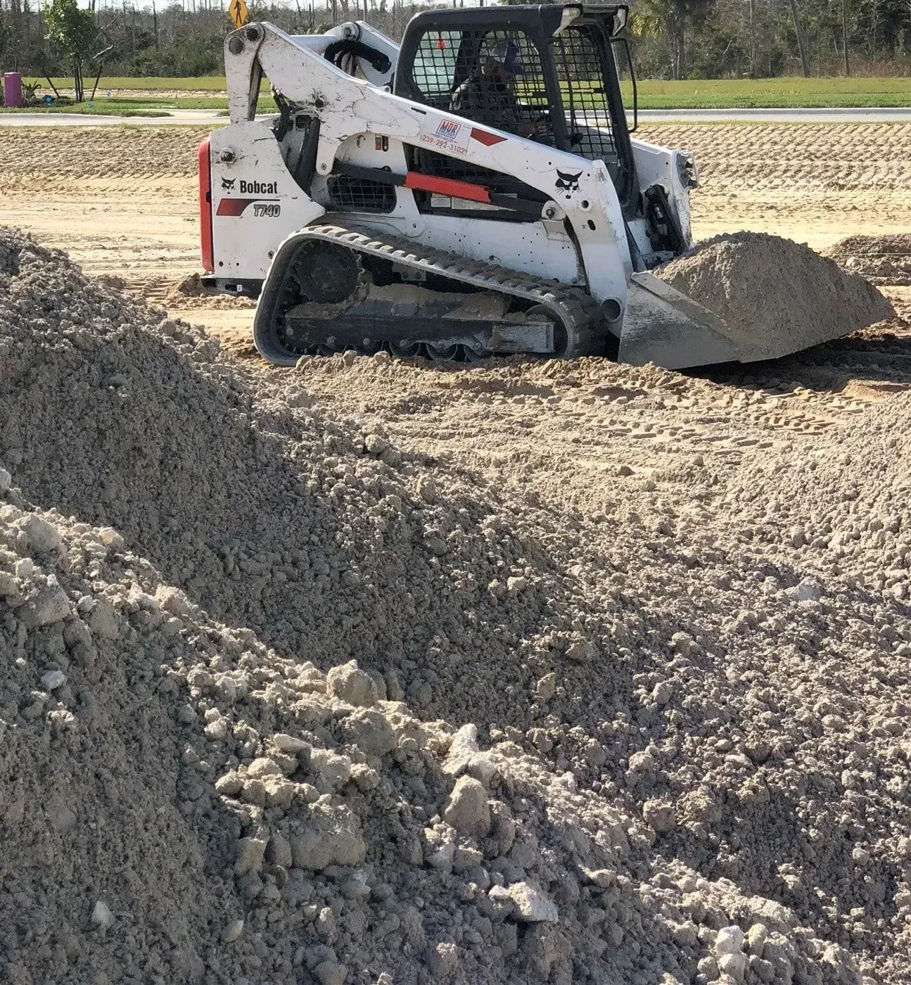 White skid-steer loader pushing gravel on a construction site