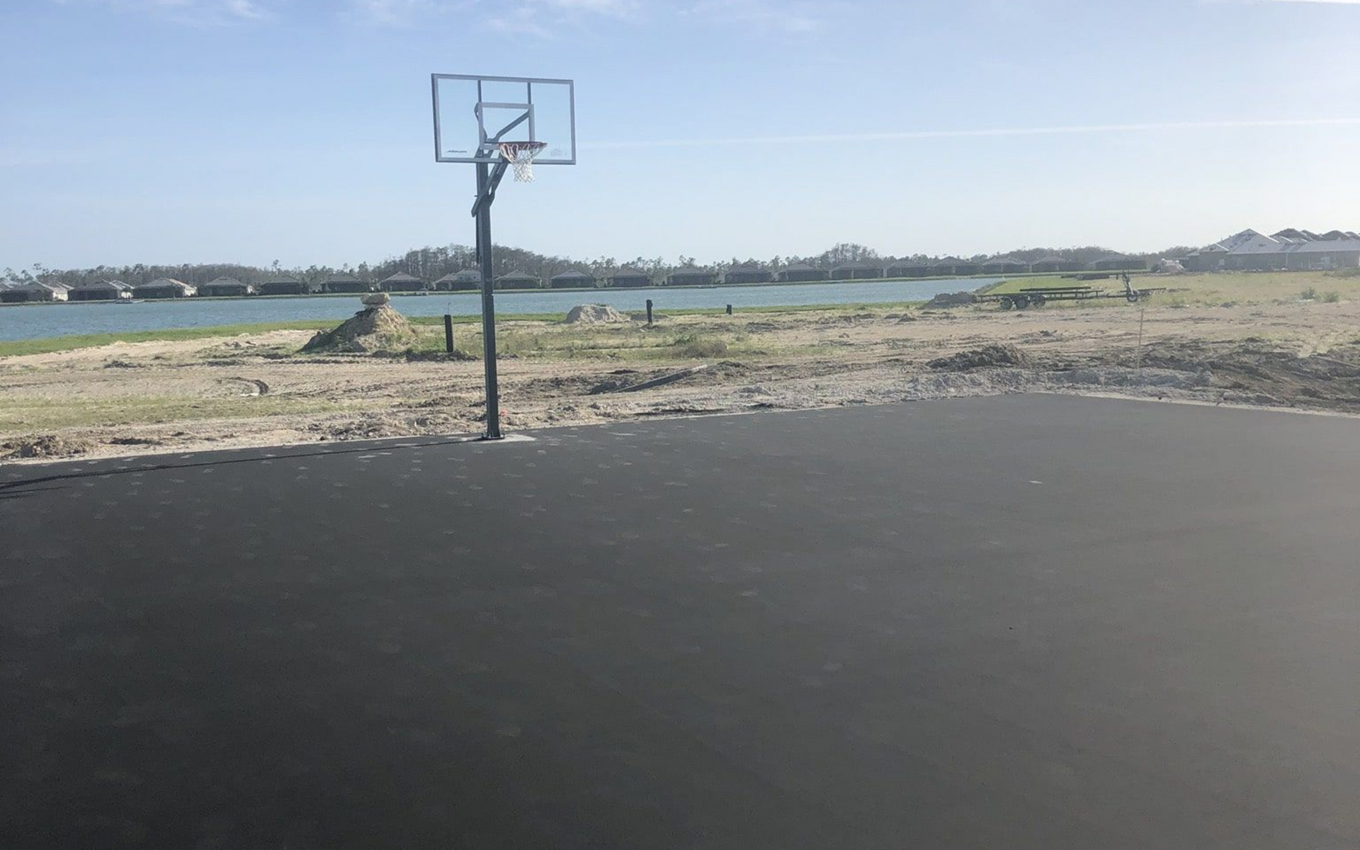 Outdoor basketball court beside a rocky shoreline under a clear sky